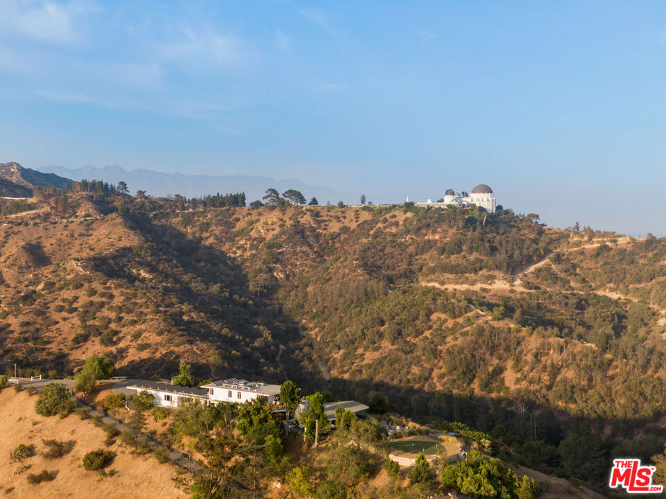 A once-in-a-lifetime preeminent Los Feliz mountain top property, 'The Oaks Estate' is the Crown Jewel of 'The Oaks' neighborhood of Los Feliz, overlooking historic Hollywoodland, Los Feliz & Griffith Park, also known to be a major celebrity enclave and former home to many A-list celebrities. The Oaks Estate is a nearly 15 acre mountain summit overlooking all of Los Feliz and the entire westside of Los Angeles. With 360-degree unobstructed Jetliner views of the entire eastern end of the Santa Monica Mountain range including legendary and iconic head-on LA landmark sites such as the Hollywood Sign, Griffith Park Observatory, Downtown Los Angeles and all the way west with ocean views of the coastline, Santa Monica Bay, Palos Verdes and Catalina. Extremely coveted with only four private owners in the past 77 years. Ideal single ownership with development potential for a new estate while incorporating the existing home as a guest residence creating one of the most special and secure *compound estates in all of Los Angeles (*lot subdivision is required, submission for subdivision permit currently under process). Other development possibilities exist (buyer to verify through their own investigations and due diligence). The Oaks Estate includes an rehabilitated 4 + 4 apx 4,000sf original 1952 mid-century modern masterpiece by Kenneth N. Lind. The Oaks Estate offers an extraordinarily and singularly unique legacy property with A+ location, acreage and legendary Hollywood significance impossible to replicate today.