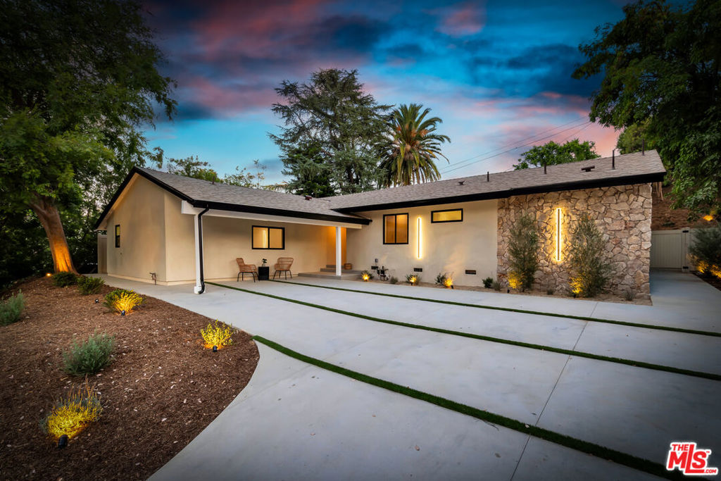 Meticulously rebuilt from the studs, this beautifully reimagined 4-bedroom, 4-bathroom single-story home blends modern elegance with timeless design in one of Woodland Hills' most desirable neighborhoods. Step inside to a bright, open-concept floor plan with soaring ceilings and abundant natural light. The spacious living spaces feature a striking natural stone accent wall, custom fireplace, LED lighting, and an oversized mirror that brings depth and sophistication. Perfect for both everyday living and entertaining, the seamless flow connects the living, dining, and kitchen areas effortlessly. The chef's kitchen is a true centerpiece boasting Taj Mahal quartzite countertops, high end, stainless steel appliances, and sleek glass-paneled cabinetry with integrated LED lighting. The luxurious primary suite offers direct access to the backyard oasis through sliding glass doors. It includes a custom walk-in closet and spa-like bathroom with double sinks and a soaking tub ideal for relaxing in comfort and style. Enjoy the California lifestyle in the private backyard, complete with a sparkling remodeled pool perfect for outdoor entertaining or quiet relaxation. The expansive driveway offers ample parking, while the attached JADU equipped with kitchen and large walk in closet, provides incredible flexibility as a rental, guest suite, home office, gym, den or creative space. Located close to shopping, dining, transportation, and top-rated schools, this exceptional home offers the perfect combination of luxury, functionality, and location.