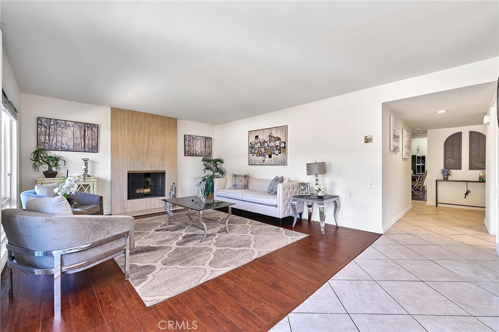 This beautifully maintained 2-bedroom, 2-bath home offers a perfect blend of comfort and style. Step into a bright and inviting space featuring fresh new paint, a spacious entry with large tile flooring, and wood-look flooring throughout the main living areas. The cozy fireplace in the living room creates a warm focal point, while dual-pane windows bring in abundant natural light. Enjoy relaxing or entertaining on the expansive private balcony, perfect for taking in the serene surroundings. The open-concept living and dining area is filled with sunlight, making this home feel airy and cheerful. Located in a tranquil, tree-lined setting with access to resort-style amenities including golf, swimming, fitness centers, and more, this home offers the best of 55+ living. Don't miss your chance to enjoy the Laguna Woods lifestyle!