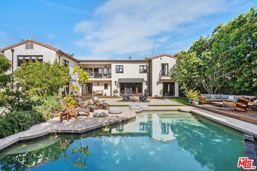 This 1920s Hancock Park Spanish Villa, reminiscent of a Santa Barbara resort, is California living at its finest. The professionally designed, low-maintenance front garden sets the tone with its organic plantings of breezy acacia trees and silvery-green olives entwined with fragrant herbs and sage bushes. The home's exterior features the original architectural elements of Malibu tiles in coastal earth tones and amber-colored stained glass windows. Welcoming you inside is a grande two-story entryway. To the left is a formal living room with an original beamed ceiling, an inviting fireplace, elegant parquet wood floors, and folding French doors that open to an outside courtyard with two distinct gathering spaces. You can dine al fresco all year round under electric space heaters on the ceramic-tiled dining patio. Or retreat to zen on the side patio with a trickling water fountain, lush bamboo, and a cozy firepit surrounded by built-in seating. Here, you can kick back for movie night or watch the big game on the outdoor TV. Across the courtyard from the living room is the family room, which has a drop-down movie screen and a built-in projector. Behind the family room is a multi-purpose room with a half-bath, perfect for an office/gym or playroom. Unfolding from the family room is a powder room and a large kitchen with multiple workstations, a breakfast area, walk-in pantry, high-end appliances, a butler's pantry, and a wine room. A formal dining room looks out to the tranquil front garden. An additional guest bedroom, office, and full bath complete the first floor. Make your way up the curved staircase, and you will enter a deluxe primary suite with two large walk-in closets, a spa-inspired bathroom with a steam shower, and a soaking tub. A private patio off the main bedroom overlooks the expansive backyard, where a small orchard of fruit trees evokes the romance of a western ranch. Rounding out the upstairs are two bedrooms connected by a Jack-and-Jill bathroom, a laundry room, and an additional bedroom with an ensuite bathroom. Now let's go out back! Towering ficus and boxwood hedges create an organic and serene enclosure with everything you need to host special events, family gatherings, or enjoy a day in the sun. Relax, take a dip in the saltwater pool and spa, fire up the BBQ in the outdoor kitchen and dining area, or gather around and cook S'mores over the camper's firepit. A guest casita with panoramic, tree-top views and a private patio is lofted above the oversized two-car garage. A rare opportunity to buy a home with so much charm in the historic neighborhood of Hancock Park. Main house is approximately 5,745 sq.ft. and the guest house is approximately 500 sq.ft.