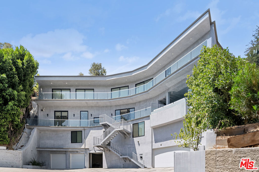 Welcome to 6181 Temple Hill Drive, a striking modern architectural masterpiece perched in the coveted Hollywood Hills. Encompassing nearly 5,700 sq ft, this 5 bedroom, 6 bath estate seamlessly fuses bold contemporary design with luxurious amenities, all framed by endless panoramic city and canyon views. The interiors are defined by sleek ceramic flooring, soaring ceilings, and expansive accordion glass doors that blur the line between indoors and out. At the heart of the home, a chef's gourmet kitchen with a grand breakfast bar, Italian stone surfaces, and top-of-the-line Wolf appliances flows into the light-filled dining area and spacious living room. Just steps away, a sparkling pool creates a resort-like backdrop ideal for stylish entertaining. A true showpiece, the residence features 2 pools: one gracefully set beside the main living area, and the other crowning the rooftop terrace with sweeping sunset views that transform every evening into a private retreat. Each of the 5 bedrooms offers a sanctuary of its own, complete with en-suite baths, walk-in closets, and private balconies. The primary suite is a pinnacle of sophistication with a spa-inspired bath, boutique-style closet and dressing room, and secluded terrace. Additional amenities include a state-of-the-art home theater, two private elevators, a five-car garage, and a fully integrated smart security system with motorized metal shutters. Perfectly positioned just minutes from the 101 freeway, world-class dining, shopping, and entertainment, this estate offers not only a home, but a lifestyle defined by elegance, innovation, and breathtaking surroundings.