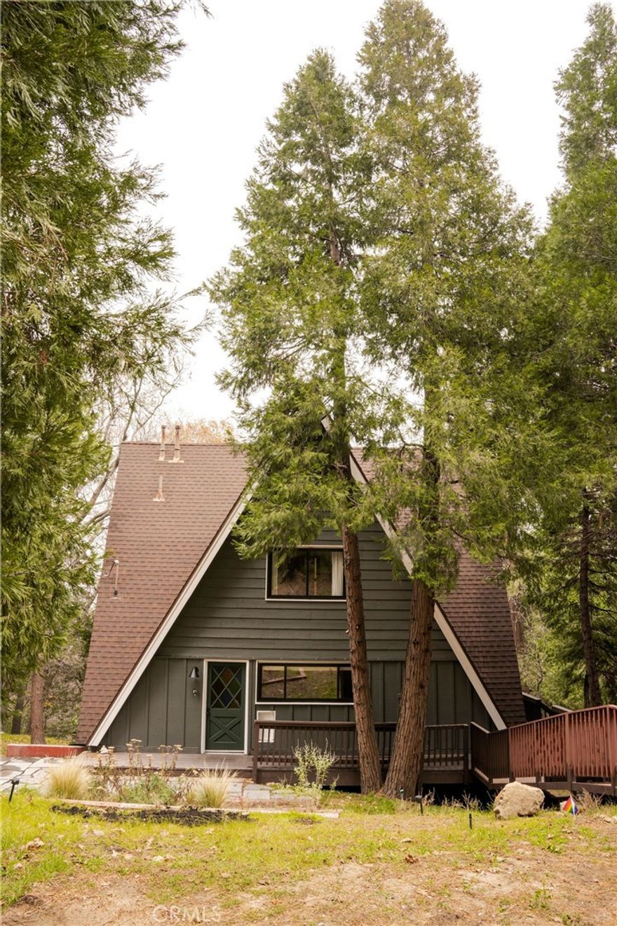 Fall in love with this enchanting 1960s A-frame, a true architectural gem that blends vintage character with thoughtful updates. This beautifully maintained 3-bedroom, 3-bathroom home features vaulted ceilings, original stained-glass accents, and sits on a generously sized lot with lush landscaping and standout outdoor living. On the main level, you’ll find a spacious living room with a wood-burning stove, perfect for cozy evenings. The original primary bedroom on this level is currently being used as a warm and inviting den, complete with its own private entrance and en-suite bath with a soaking tub—offering flexibility for guests or creative use. The galley-style kitchen is full of charm and functionality, with easy access to the living areas and outdoor spaces. Upstairs, two guest bedrooms offer cozy comfort with views of the home’s iconic A-frame design. The lower level features a private, oversized bonus suite, currently used as a bedroom/office, featuring a brand-new sliding door, its own concrete patio, and a bathroom—ideal for work, hosting, or quiet retreat. Step outside into your dream backyard, now featuring a brand-new wood fence enclosing the beautifully landscaped yard with stone pavers—a perfect space for entertaining, relaxing, or enjoying the peaceful mountain setting. A new AC system provides year-round comfort, and dual access points (front entry and driveway) make parking and hosting easy. This rare A-frame offers style, flexibility, and outdoor living at its finest—truly a one-of-a-kind mountain getaway.