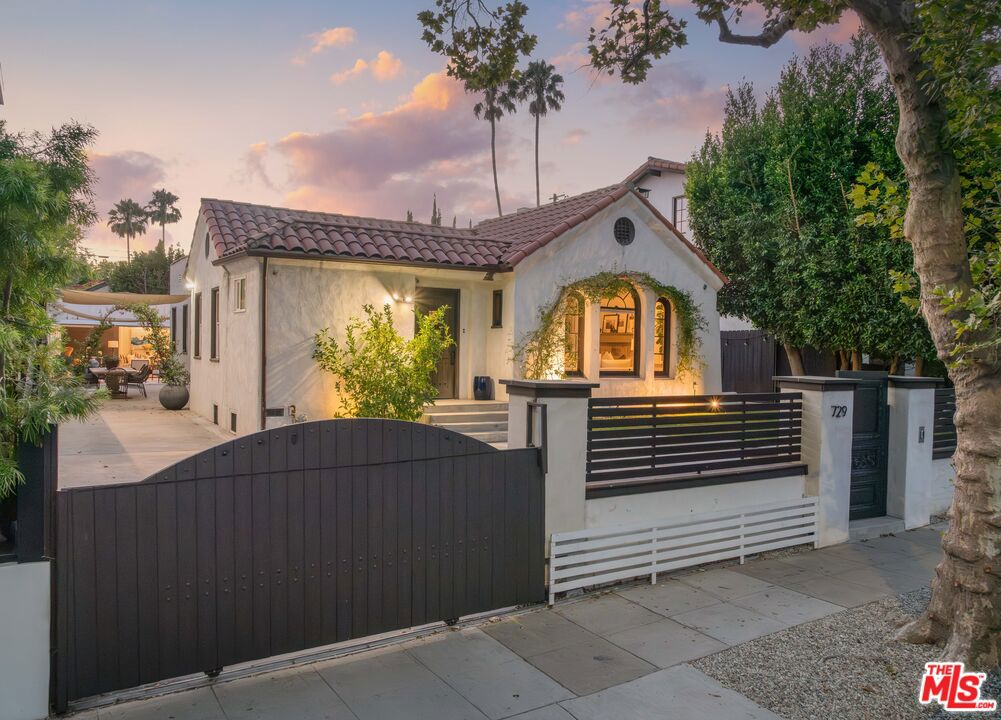 Located on a sought after tree lined street and fully gated to ensure true privacy, 729 North Stanley is a stunning Spanish home with beautiful modern appointments and thoughtful original detailing. Upon entering the house, one is met with the wonderful and expansive scale of the living room accompanied by high coved ceilings, gleaming hardwood floors, and a gorgeous Batchelder gas fireplace. The chef's kitchen is lined with the highest quality custom Showcase cabinets by Peter Scholz. It is complemented by a stunning built in banqueted that makes for a little swanky retreat from the hustle and bustle of the living room. The two full bathrooms have been stylishly renovated with timeless design featuring high quality finishes and fixtures through out. Across the lush grassy backyard is approximately 300 square feet of additional space in the detached garage that has been used as a versatile office and is complete with custom glass and iron bifold doors that open to create a seamless indoor-outdoor retreat. This sophisticated and charming home is well located and an easy stroll to countless places that breathe life into the Melrose neighborhood. There is no other area where walking destinations include major grocery stores like Erewhon, Whole Foods, Trader Joe's, The Grove, and over 15 beloved local cafes such as Pantheon, Olive and James, Blue Bottle, Coffee Commissary and well over 200 eating establishments including everything from breakfast spots to Michelin-recommended dining rooms.
