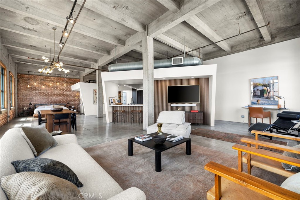 Originally built in 1925 as the landmark S.H. Kress Department Store, The Kress Lofts remain one of Long Beach’s most iconic residential conversions—where Beaux-Arts architecture meets modern urban living. Set in a coveted corner position on the eighth floor, Unit 8D has been dramatically reimagined, blending industrial volume with refined finishes and elevated functionality. The brand-new kitchen is a showpiece, featuring bespoke walnut cabinetry, Taj Mahal honed stone countertops and backsplash, an oversized island with bar seating, and a full suite of stainless steel appliances. Both bathrooms have been thoughtfully remodeled—the primary with a marble walk-in shower and additional built-in storage, and the powder room with a striking green tile feature wall. Throughout the loft, soaring 15-foot ceilings, exposed brick, concrete floors, and massive warehouse-style windows pay homage to the building’s original character while capturing exceptional light and breathtaking views of the city and morning sunrises. New contemporary light fixtures add sculptural drama, while Alexa-enabled smart home features allow intuitive control of lighting, audio, and the newer HVAC system. Gorgeous millwork and a beautiful new gallery television adds to the home’s polished sophistication. One of the few units to offer modern climate control and premier deeded parking, this loft also includes generous storage throughout, a spacious walk-in closet, an elevated sleeping loft for overnight guests or creative use, and an in-unit washer and dryer. The building features secure entry, a rooftop lounge with panoramic views and BBQ area, and an unbeatable location in the heart of downtown—just moments from restaurants, shops, galleries, transit, and the waterfront. Eligible for Mills Act tax benefits, Unit 8D is a rare opportunity to own a historically significant space that lives effortlessly modern.