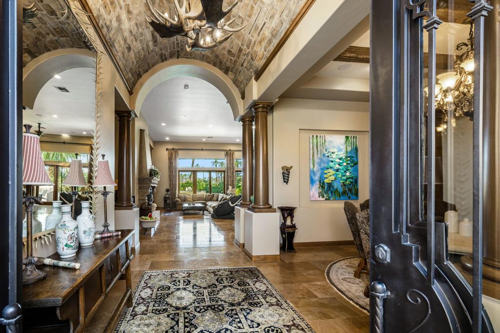 A true European-inspired retreat in the heart of the desert, this exceptional 4,337 sq ft residence in the exclusive Palms Country Club combines refined Old-World elegance with contemporary comfort and commanding views. Set on an interior fairway with no homes across the 7th hole, the property captures sweeping vistas of the lush green course, sparkling lake, and dramatic Santa Rosa Mountains. Crafted with exquisite attention to detail, the home is rich with architectural character--arched passageways, soaring beamed ceilings, extensive stonework, and stately columns create a sense of timeless charm. Inside, you'll find travertine flooring, multiple fireplaces, beautiful wood built-ins, granite slab countertops, custom cabinetry, and detailed mosaic inlays throughout. The expansive Great Room floor plan is ideal for both relaxing and entertaining, featuring a full sit-down bar and seamless flow to the outdoor living spaces. The chef's kitchen includes a commercial stovetop, stainless steel appliances, a custom flume hood, and a generous center island. The luxurious primary suite offers two spacious walk-in closets, a romantic fireplace, and a spa-like bathroom with a sunken tub framed in marble, complete with its own fireplace for added ambiance. Step outside to a spectacular resort-style setting: a large pavered patio, pool and spa with cascading water features, built-in BBQ, firepit, and multiple seating areas--all designed to enjoy unforgettable desert sunsets. The detached casita with private entrance offers beautifully appointed guest accommodations. Additional highlights include a 600+ bottle temperature-controlled wine cellar, custom window shutters, a 3-car garage, and a beautifully landscaped lot over a quarter acre. A rare blend of privacy, sophistication, and stunning natural beauty--this is desert living at its most refined.