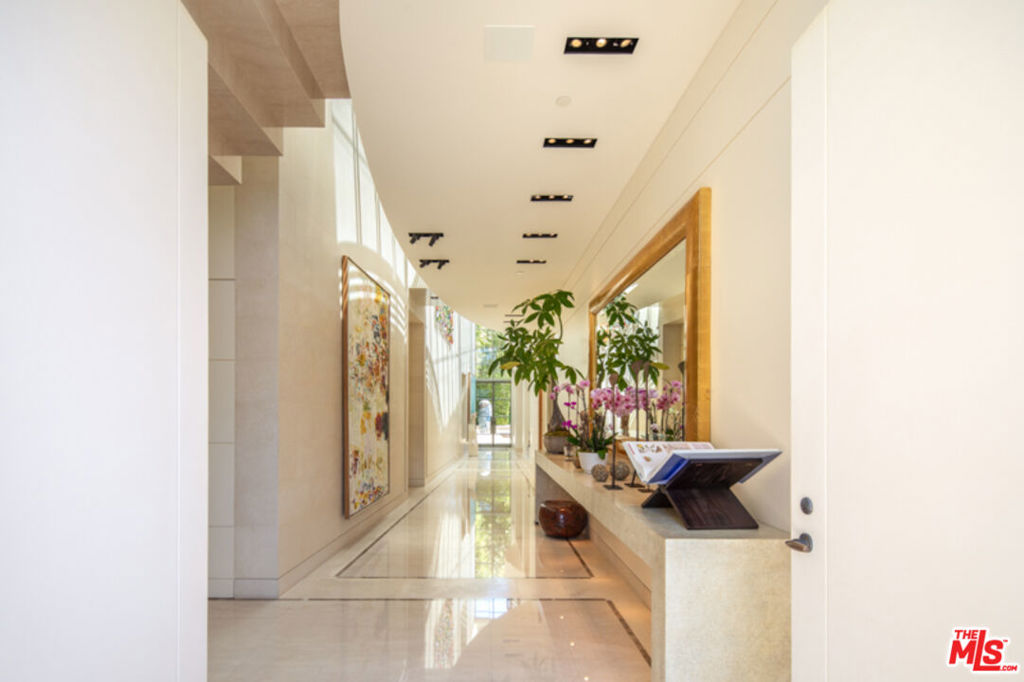 Tucked behind gates in the prestigious estate section of Beverly Hills, this striking architectural contemporary which has been meticulously renovated by the world renowned designer, Roger Thomas, offers a rare combination of design pedigree, refined finishes, and total privacy. A true jewel box, once home to one of the world's most renowned art collectors, the residence is fit with museum-quality lighting throughout, showcasing its interiors as a gallery in their own right. The five-bedroom, five-and-a-half-bath home spans expansive, light-filled spaces, with soaring ceilings, limestone and parchment clad walls, and exquisite detailing throughout. A beautifully appointed study offers a quiet retreat, while grand formal and informal living spaces flow seamlessly to the outdoors. Elevator access and dual laundry rooms on the upper and lower floors ensure seamless ease of use. The entertainer's yard is an oasis unto itself lushly landscaped with a mosaic tiled pool, and anchored by a stunning gazebo overlooking the grounds and residence. Mature ficus lining the entire property ensure the utmost seclusion. With an unmatched level of finish, light, and privacy, this is a rare offering in one of Beverly Hills' most sought-after enclaves.