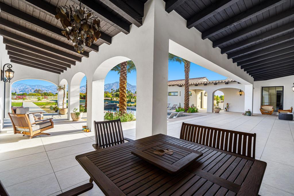 Rare opportunity to own a new build in La Quinta Polo Estates. Welcome to desert luxury at its finest nestled behind two private gates on a 2.5 acre custom lot, this 5-bedroom, 5.5-bath tennis estate blends modern elegance with touches of old-world charm. Step into a sweeping open floor plan with natural light, highlighted by soaring 18-foot ceilings and a dramatic custom double-sided bookmatched marble fireplace, comprised of six slabs. 42'' x 42'' Porcelain tile throughout the home, with Italian marble gracing the entryway and library. The gourmet kitchen is a culinary dream, featuring high-end appliances - Miele double wall & steam ovens, with Miele vacuum sealer drawer, Wolf induction cooktop, Gaggenau fridge and freezer columns, Fisher-Paykel double dishwasher drawers & wine cooler in walk-in pantry. Quartzite countertops, island, custom marble backsplash and an expansive island perfect for entertaining. The triple garage includes an electric vehicle charging outlet for modern convenience. Retreat to the private primary suite with serene mountain views and direct patio access. The spa-like ensuite stuns with two 6-foot, single-slab marble vanities with integrated sinks just one example of the 300k in luxury stone upgrades found throughout the home. Additional highlights include: Detached guest casita, custom library, spectacular home theater with short-thro projector, tennis/pickleball court and a sparkling pool and spa. Enjoy seamless indoor-outdoor living, whether lounging poolside, playing a match on your private court, or taking in the unrivalled mountain vistas while relaxing on the expansive covered horseshoe loggia. The home was thoughtfully set back from the entry gate to enhance privacy and curb appeal. Equestrian friendly - zoning allows up to four horses. Close proximity to convenient shopping, restaurants, Desert International Horse Park, Eldorado Polo Club and Coachella Valley's festivals. Don't let this gem slip away. Call today!