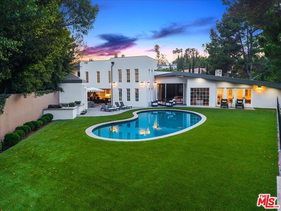 The Weinhart Estate. For the first time in nearly three decades, this rare architectural jewel crafted by the renowned Edward H. Fickett, FAIA comes to market. Often hailed as the "Frank Lloyd Wright of the 1950s," Fickett designed each residence as a bespoke work of art, harmonizing site, materials, and lifestyle. Set on an elevated corner lot in the tranquil hills above the flats, the home offers the perfect blend of privacy, pedigree, and location. Clean mid-century lines, soaring beamed ceilings, and walls of glass capture panoramic canyon views while seamlessly merging indoor and outdoor living. The residence unfolds with a dramatic pivoting front door, expansive living spaces anchored by a striking stone fireplace, and a 40-foot chef's kitchen outfitted with a 12-foot island, dual Wolf induction ranges, Sub-Zero refrigeration, and book-matched statuary marble. A marble-topped wet bar, sophisticated den, and thoughtfully designed entertaining areas reflect the era's timeless glamour. Upstairs, the skylit primary suite features a private balcony, marble fireplace, dual walk-in closets, and a spa-like bath. Additional guest suites echo the home's architectural integrity. Outside, lush landscaping surrounds a Pebble-finish pool, built-in barbecue, and multiple terraces for alfresco dining and lounging. An extraordinary opportunity to own an authentic piece of mid-century heritage in one of Beverly Hills' most coveted settings just moments from the iconic Beverly Hills Hotel and the world-renowned shops and dining of Rodeo Drive!
