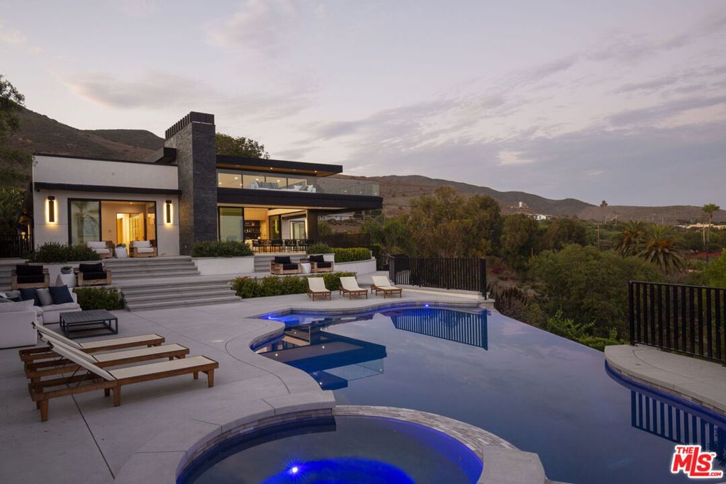 Oceanview Excellence in Architectural Form. Minutes from Zuma Beach, this extraordinary estate captures the essence of refined coastal living with striking modern architecture, thoughtful design, and panoramic ocean views. Framed in durable steel for structural integrity and longevity, this newly constructed home is a harmonious blend of sophistication, comfort, and innovation. Soaring 10-15 ft ceilings and complemented by white oak floors, custom-milled doors, clerestory windows, and a sculptural glass staircase - all designed to frame and amplify the stunning, uninterrupted coastline views from nearly every room. State-of-the-art chef's kitchen, 2-story living room with dramatic marble fireplace, 100+ bottle wine display and marbled wet bar bring sophistication and functionality. The ocean-facing primary suite is a tranquil haven with a luxurious marble shower, soaking tub, and a generous walk-in closet. There are 4 add'l ensuite bedrooms on the main floor and a flexible bonus loft with bath and private balcony offering a quiet space for relaxation or creativity. Expansive terrace and infinity-edge pool with cascading waterfall and hot tub offer breathtaking ocean vistas. An al fresco dining area, outdoor fireplace, mature citrus trees and vineyard with potential to produce up to 1,500 bottles annually adds the finishing touch for the resort-like experience. A North/South night lit tennis court completes this home in addition to a structure perfect for a gym, game room, or private guest unit. With 6 bedrooms, 7.5 bathrooms, sweeping terraces, and gated parking for 10 vehicles, this estate is built for intimate coastal living and grand-scale entertaining.