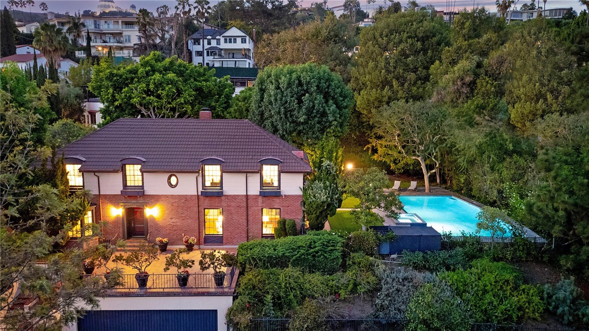 Tucked away in one of Los Feliz’s most coveted neighborhoods, this private residence offers timeless elegance. Behind a gated entry, discover a serene sanctuary featuring a sparkling pool, expansive backyard, and lush greenery.
Inside, light-filled living spaces flow effortlessly, highlighted by refined finishes, custom details, and a classic floor plan. There is a cozy den with fireplace, bar and door out to the garden. Living room with high ceiling has multiple sets of French doors which open to the patio and beyond. Updated kitchen with charming breakfast nook overlooking the garden. Primary suite offers a retreat of its own with a spa-like bath, oversized walk-in closet, a Juliet balcony and views of the sparkling city lights. Every bedroom is en-suite (all recently remodeled). One bedroom on the main floor serves well as an office.
The backyard is truly the showstopper—ideal for entertaining with a sparkling pool/spa, lush mature landscaping, and an expansive lawn perfect for gatherings or quiet relaxation under the stars. Whether hosting friends for a game of croquet, summer pool parties or enjoying quiet mornings in the garden, this outdoor oasis offers the best of LA living.
3 car garage. Additional lower level bonus space approx. 360 sqft currently used as a gym but can serve as a separate apartment with its own private entrance.
Just moments from Griffith Park, culinary eats, trendy boutiques, and the city’s best culture, this home offers the rare opportunity to own a true jewel in the heart of Los Angeles.