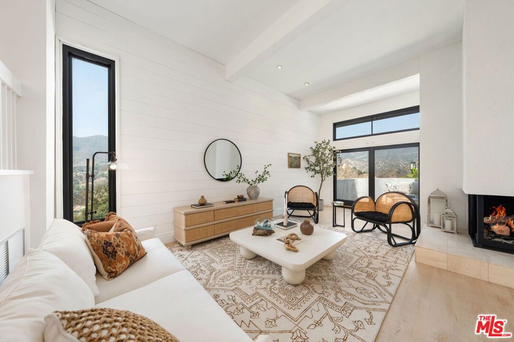Tucked in the coveted Palisades Highlands, this sun-drenched townhome offers sweeping canyon views and stylishly updated interiors in one of the most serene settings on the Westside. With 3 bedrooms, 2.5 bathrooms, and 1,857 square feet of beautifully finished living space, this is the premier view unit in the Michael Lane Villas.Beyond the private front patio, the main level unfolds into a warm and inviting living room with soaring vaulted ceilings, a dramatic fireplace, and striking bleached wood floors. Expansive windows and a thoughtfully placed skylight flood the home with natural light, while framing unobstructed vistas of the surrounding mountains and canyon. The updated kitchen is outfitted with new appliances and opens to a charming breakfast nook perfect for morning coffee or casual entertaining. Upstairs, the spacious primary suite offers vaulted ceilings, a second fireplace, dual closets, and more of those coveted canyon views. The en-suite bath has been refreshed with new lighting and hardware for a clean, timeless look. Two additional bedrooms share a bright, updated bathroom. With a generous two-car garage and access to the community's resort-style amenities including pool, spa, and fitness center this turnkey retreat offers the perfect blend of privacy, comfort, and convenience just moments from the Palisades Village, hiking trails, and the beach.
