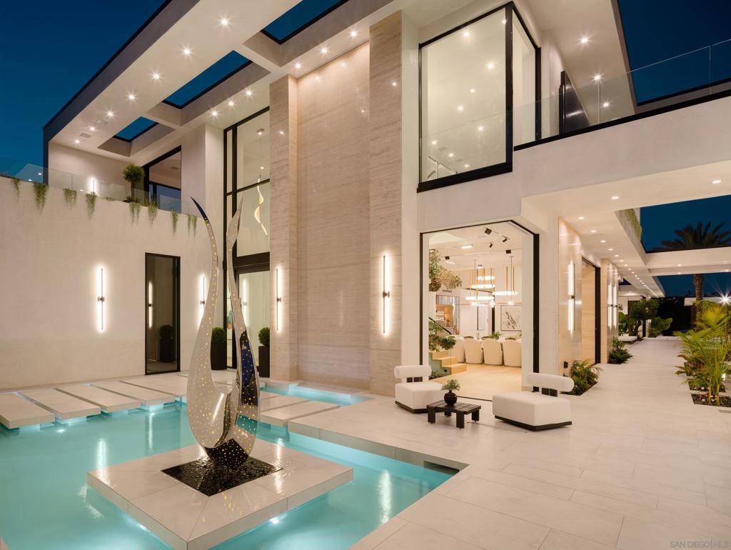 Perched in the heart of the esteemed Muirlands, this fully double gated estate built for privacy and security, features custom aluminum modern gates that open to a double courtyard motor court with custom glass doors and oversize garages, adding a touch of exclusivity to this architectural marvel. This one of a kind residence stands as a bold testament to architectural brilliance and luxury living. A true masterpiece of modern design featuring soft tones, soaring ceilings, and a flawless fusion of sleek lines and warm natural accents. This is more than a home; it is an unparalleled expression of contemporary elegance and timeless sophistication, setting a new standard for opulent living in San Diego. At first glance, the scale of the residence is awe-inspiring, with towering 19-foot ceilings that amplify the sense of space and light throughout. A grand courtyard entry sets the tone, featuring a tranquil reflecting pond, stainless steel sculpture, and a stunning 26-foot water feature adorned with travertine slabs—an exquisite welcome that encapsulates the home's commitment to timeless design. Inside, 11-foot glass pocket doors and clear story windows effortlessly blend indoor and outdoor spaces, inviting natural light to play across sleek, modern interiors. The Southern exposure bathes each room in warmth, complemented by cantilevered steel beam construction that spans the entire length of the residence, showcasing a harmony of form and function rarely seen. The main level epitomizes luxury with its maid quarters, three en-suite guest bedrooms, and a primary suite complete with a designer closet that exudes spaciousness and elegance. White oak floors and Italian Kitchen-designed cabinets underscore the home's commitment to quality craftsmanship, while a double travertine island and top-of-the-line Miele appliances grace the expansive main kitchen along with a Thermador professional grade prep and catering kitchen, ensuring culinary excellence at every turn. Designed with entertainment in mind, the lower level is a haven for leisure and recreation, featuring a state-of-the-artFull Swing Golf and Sports simulator, a 12-person movie theater, temperature controlled wine cellar and display, and a full-sized gym complimented by a dry sauna and steam room. A bar and billiards room offers a sophisticated space for gatherings, while the adjacent flat, usable yard beckons families with its potential for outdoor activities and additional amenities like a sports court. Outside, the 60 ft pool stands as a focal point of the main level amenities, with its brilliant pure white finish, baja shelf and spa. The custom swim-up bar features a full kitchen, complete with a U-shaped wraparound travertine slab bar and full outdoor kitchen and fireplace. The ambiance continues to enchant with a one bedroom guest house, complete with its own kitchenette and living area. Tropical landscaping surrounds the majestic pool, outlined by beautiful olive trees, walls of lush green hedges that guarantee total privacy. Ascending to the top level reveals a staircase adorned with a remarkable 300-year-old olive tree, guiding residents to a spacious office or art studio, accompanied by a versatile flex room ideal for a library, music room, or lounge area. Evenings come alive in the outdoor movie theater with a 148" YOLO outdoor television, complemented by an additional outdoor kitchen and fireplace, perfect for hosting unforgettable gatherings under the stars. The property features a smart home full automation RTI system inclusive of 32 security cameras and Doorbird gate systems, 79 surround sound speaker system, Lutron lighting system, pre-wired for custom blinds, complete VRF multizone Daikin HVAC system, and touch screen capabilities from Ipads throughout the property as well as your personal mobile device for remote access. With a doublewide and double height garage on each of side of the house the garage has the capability of becoming a 4 car garage on bot...