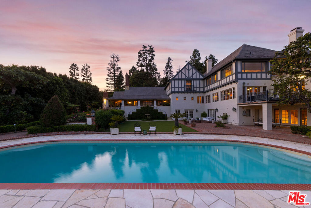 NEWLY PRICED!!! Nestled upon a cul-de-sac in the prestigious enclave of lower Bel-Air, overseeing awe-inspiring panoramas of the Bel-Air Country Club Golf Course, stands 543 Perugia. Double gates and a winding drive lead into this 9,615sf, three-story, elegant work of Tudor craftmanship, offering 5 bedrooms, 5 bathrooms and 2 power rooms. The expansive motor court, framed by towering trees and lush foliage, provides a serene, inviting entrance. Enter the grand foyer, seamlessly connecting to the formal living room, replete with a dramatic stone fireplace, exposed wood beam ceiling and generous covered terrace showcasing Bel-Air Country Club golf course fairway views and beyond. The elegant formal dining room with architectural crown molding and discreetly concealed storage paneled walls effortlessly flows into a secluded terrace and garden area. The bright chef's kitchen features an adjoining breakfast area, oversized island, walk-in pantry and butler's pantry. The exceptional entertainment lounge, generously proportioned to accommodate gatherings of distinction, boasts a grand wood fireplace, speakeasy-style hidden wet bar, custom shelving and original wood flooring, all enveloped by walls of windows and a terrace that frames the land and cityscape views. An adjacent art studio or bonus room offers an idyllic retreat for creativity and inspiration. Ascend the stairs to the second floor, where the light-filled primary suite awaits, featuring a striking wood and marble fireplace, vast terrace with scenic beauty and bathroom suite complete with sauna, soaking tub, standup shower/bathtub and spacious walk-in closet. An open area on the landing provides a versatile space for an office/den. An additional guest bedroom suite completes this floor. The lower level of the residence encompasses three more bedroom suites, a three-car garage, utility room, recreation room with wet bar and fireplace and a covered terrace. An elevator discreetly serves all floors. The romantic meticulously landscaped grounds offer a swimming pool and spa, outdoor BBQ area, rose garden and ample parking. Thoughtfully designed for private hosting and entertaining, this prime Bel-Air estate presents enticing opportunities for customization and modernization to bring your unique vision to life.