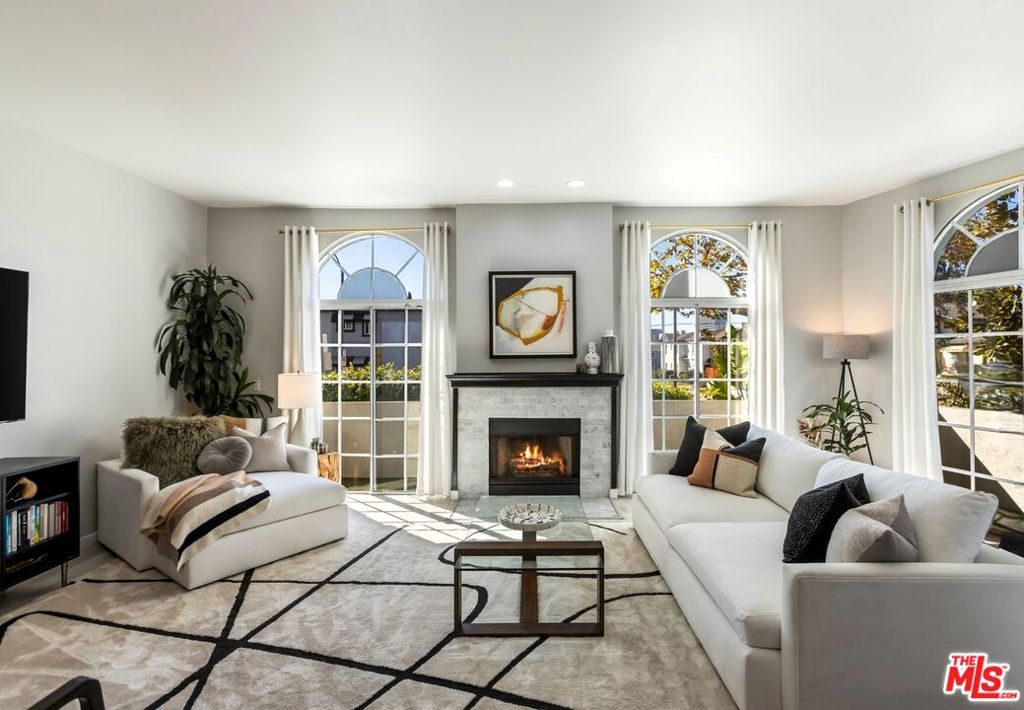 The one you have been waiting for. California casual sophistication defines this highly desired corner residence, showcasing gleaming plank flooring throughout, soaring ceilings, recessed lighting, and an abundance of natural light. Enter through the inviting foyer into the dedicated dining area, highlighted by an impressive tray ceiling and custom light fixture, which flows seamlessly into the expansive main living space. Here, an elegant marble fireplace with wood mantle, convenient wet bar with shelving, and dramatic floor-to-ceiling glass doors open to a collection of intimate balconies perfectly merging indoor and outdoor living. The well-appointed kitchen boasts considerable cabinetry, stainless steel appliances, and a wine refrigerator, while a chic powder room completes the main level. Upstairs, the serene primary suite offers a spacious bedroom, stylish closet, and dazzling ensuite bath with dual vanity, deep soaking tub, and separate shower. A comfortable sunlit second bedroom provides ample storage, while the third bedroom offers flexible potential as an office, den, or guest space. Both are serviced by a sizable hall bathroom with sleek vanity and tub-shower combination. A dedicated laundry room with full-size side-by-side washer and dryer, upper cabinetry, and additional hallway linen storage complete the second level. Perfectly situated near the Miracle Mile, LACMA, The Grove, Century City, Beverly Hills, and more, this residence places renowned dining, shopping, and entertainment right at your doorstep.
