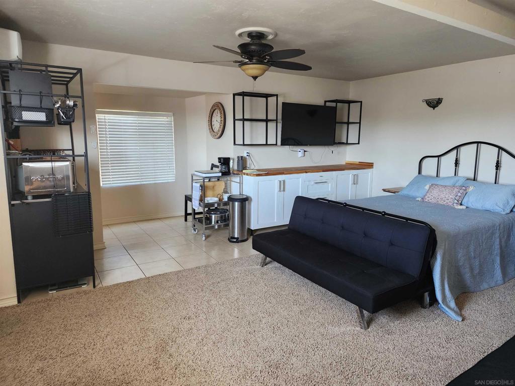 Fantastic Oceanside studio unit on west side of freeway and few blocks from the beach. This spacious upstairs studio comes fully furnished with large bed, ceiling fan, separate sitting area with chairs, full bathroom with large shower, dining table and chairs, desk/office area at top of stairs, and kitchen appliances such as refrigerator, coffee maker, microwave, utensils, and more. The unit has a spacious open floorplan yet with small alcoves for various seating and work activities. Parking is on the gated driveway steps from the entrance and all utilities are included in the rent. And, extra bonus , access to a pool and laundry