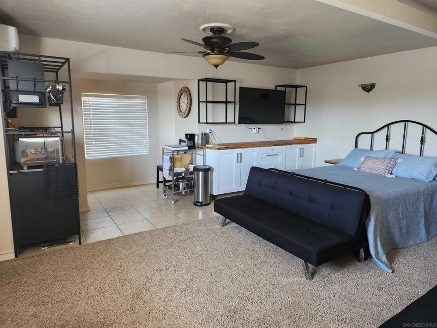 Fantastic Oceanside studio unit on west side of freeway and few blocks from the  beach. This spacious upstairs studio comes fully furnished with large bed, ceiling  fan, separate sitting area with chairs, full bathroom with large shower, dining table  and chairs, desk/office area at top of stairs, and kitchen appliances such as  refrigerator, coffee maker, microwave, utensils, and more. The unit has a spacious  open floorplan yet with small alcoves for various seating and work activities. Parking  is on the gated driveway steps from the entrance and all utilities are included in the  rent. And, extra bonus , access to a pool and laundry