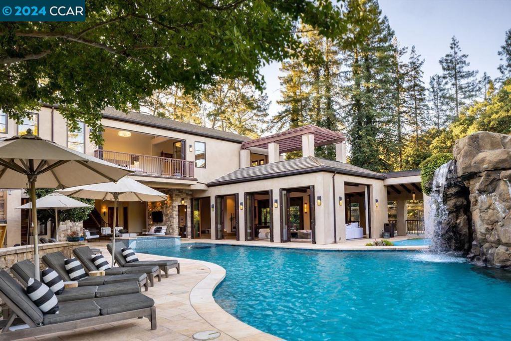 This retreat sits on a dual lot at the end of a private drive, a world away from life’s cares. The principal lot (3941 Happy Valley Road) is 2.3 acres, adjoining the undeveloped second lot (3943, .98 acre), now a garden, which can be preserved as open space or developed or sold separately. Entertain those of any age with a tennis court, basketball court, batting cage, swimming pool with waterfalls, slide, climbing wall, and water jets, golf simulator, putting green and bocce court. Relax in the massage room, two Jacuzzi spas (one in a covered grotto), hair salon, or by the outdoor fire pit, or enjoy a movie in the spacious professional theater with reclining seating. The home, with vaulted ceilings throughout, offers separate gathering areas. One melds the gourmet kitchen (with elite appliances), dining room, and spacious living room (with built-in 80” television and surround sound). Move to the other side of the house to the game room, equipped with six televisions and ample space to play pool, ping-pong, or cards. Wet bars are found on both sides of the house, and outdoor patios and terraces abound. The four bedrooms are spacious, and the luxurious primary suite offers a massive walk-in closet and an en-suite bath with every amenity.