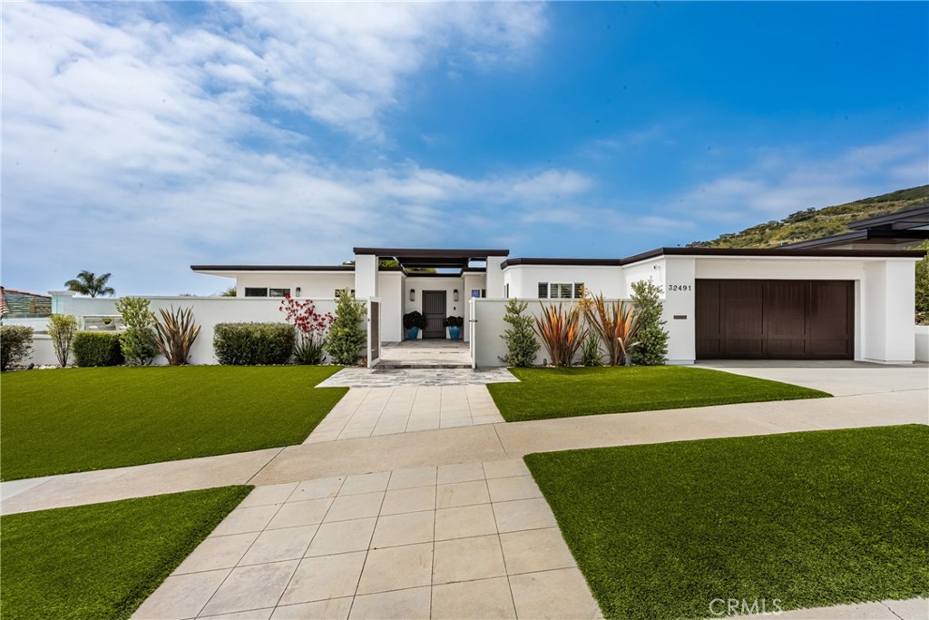 Coastal Elegance Meets Modern Luxury in Monarch Bay Terrace
Perched in the prestigious enclave of Monarch Bay Terrace, this exquisitely designed single-level ranch-style residence epitomizes refined coastal living. With four spacious bedrooms, three luxurious bathrooms, and a dedicated home office, this private sanctuary blends timeless architecture with modern sophistication—all set against a backdrop of sweeping ocean views.
Enjoy panoramic Pacific vistas from all main living areas and the serene master suite, where rich hardwood walnut floors run throughout the home, grounding each space in warmth and refinement. Retractable awnings and electronic vanishing screens soften indirect sunsets and offer effortless transitions between indoor comfort and outdoor splendor. Designed for seamless flow, the virtually stepless floor plan invites gentle ocean breezes and natural light into every corner of the home.
The fully usable, secure flat lot is a rare gem in the community. Anchored by a state-of-the-art saltwater pool shored up on a concrete foundation, the outdoor living space has been intelligently crafted to maximize both utility and luxury. A detached cabana—fully outfitted for year-round comfort—offers a shaded retreat, while built-in storage discreetly supports the wraparound putting green and manicured grounds.
Mature citrus trees grace the inland side of the home, complementing a fully equipped outdoor bar and grilling area that faces the ocean—perfect for entertaining with style and ease. Advanced 360-degree remote surveillance ensures total peace of mind, while smart design touches throughout the home reflect a commitment to elegance, innovation, and resort-caliber living.
Every inch of this extraordinary home has been meticulously curated to deliver the ultimate in privacy, comfort, and coastal sophistication.