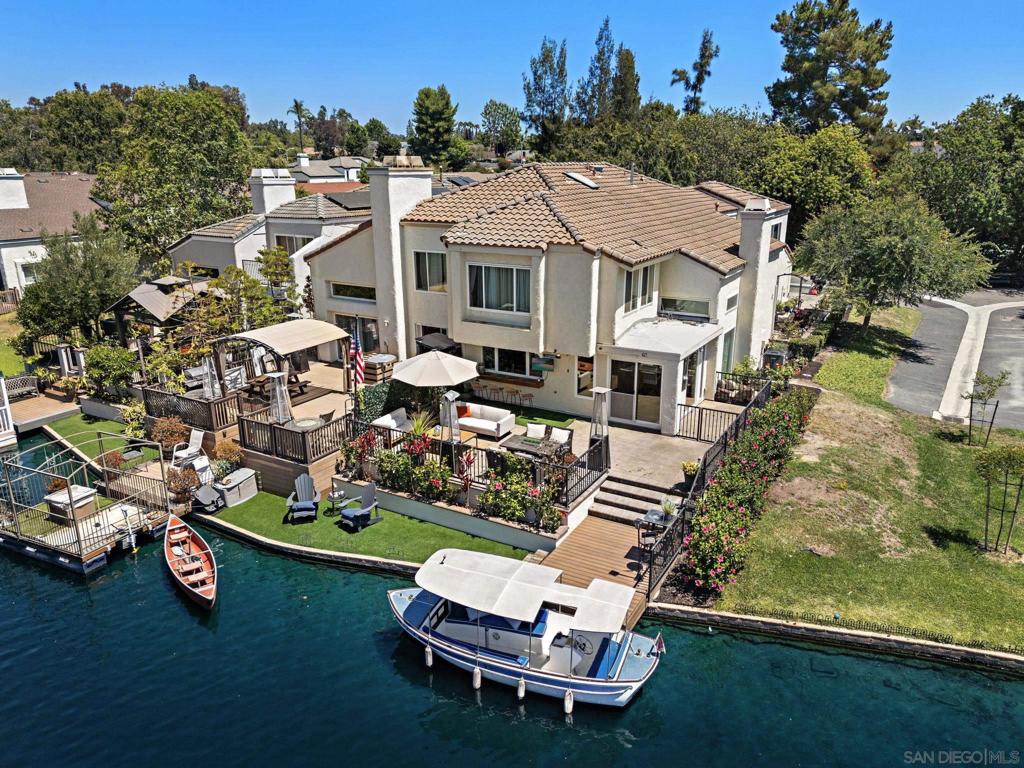 Indulge in the ultimate lakeside escape with this exquisitely renovated 4-bedroom, 3-bath waterfront residence—ideal as a luxurious vacation home or a high-demand short-term rental. Designed with sophistication and comfort in mind, this home boasts soaring vaulted ceilings, expansive windows framing sweeping lake views, and rich natural wood flooring throughout. The gourmet kitchen is a culinary masterpiece, featuring stunning quartz countertops, custom cabinetry, and premium appliances, perfect for entertaining or relaxing after a day on the water. The formal dining room and spacious loft offer versatile spaces for gatherings, work, or leisure. A private downstairs suite with its own entrance provides exceptional flexibility for guests or extended stays. The primary suite is a tranquil haven, offering breathtaking water vistas and a spa-inspired bathroom with designer touches. Step outside to a brand-new deck and immaculate, newly installed turf—creating a seamless indoor-outdoor living experience, ideal for alfresco dining, lounging, or enjoying sunset views. Your private boat is included, making lake adventures effortless. Modern upgrades such as a new tankless water heater ensure year-round comfort and efficiency. Enjoy resort-style amenities with a remarkably low HOA, including a clubhouse, fitness center, spa, tennis and pickleball courts, beach volleyball, and a pristine man-made lagoon. As a resident, you’ll have access to the exclusive yacht club, festive boat parades, and front-row seats to the area’s spectacular Fourth of July fireworks.