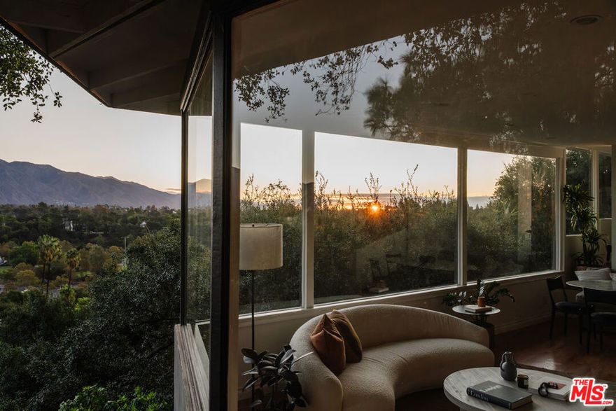 Perched on a 14,000 sf lot, this architectural work of art by W. Melville Garten offers the ultimate in privacy and refinement. Located in Pasadena's coveted Linda Vista neighborhood, this 3-bedroom, 3-bath with a guest house commands breathtaking views of the San Gabriel Mountains and the iconic Rose Bowl. Expansive windows flood the open living and dining areas with natural light, framing uninterrupted vistas that blur the line between indoors and out. At the heart of the home, the chef's kitchen boasts new quartz countertops, a wine fridge, and premium stainless steel appliances, and flows onto a spacious patio perfect for al fresco dining with sweeping views. On the main level, a versatile bedroom serves equally well as a guest room or study, paired with a nearby bathroom highlighted by a classic clawfoot tub. The lower level is anchored by a tranquil primary suite with a private deck, expansive walk-in closet, and spa-inspired bath featuring a deep soaking tub, separate dual-head shower, and double vanity. Along the same hall, a third bedroom and a den, both featuring floor-to-ceiling glass doors that open to the back deck and garden, are complemented by an updated bathroom with a soaking tub and steam shower. The backyard is a dream for outdoor living and entertaining, featuring numerous seating areas and pathways that wind through lush grounds landscaped by the incredible Chaparral Studio Gardens. The detached guest house offers the perfect retreat for visitors or a creative workspace. A two-car garage with EV charging plus three additional spaces provides ample parking. 910 Glen Oaks Boulevard embodies the rare union of architectural legacy and modern comfort, where seamless indoor-outdoor living, inspiring views, and a tranquil sense of retreat define exceptional Pasadena life.