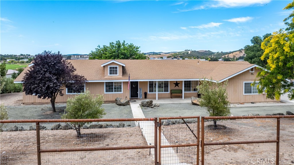 Two Homes on Almost 13 Private Acres Backing to the Salinas Riverbed with Stunning Views! Welcome to your dream retreat in Paso Robles, just outside the City Limits, but moments to town! This exceptional multi-functional property offers not just one, but two separate living opportunities, thoughtfully designed for multi-generational living, guests, or other income potential. The main residence is a stylish, 4 bedroom/2 bathroom single-level ranch-style home spanning approx. 1,873 sq ft. Enter to a spacious great room, seamlessly connecting the living, dining, and kitchen areas - ideal for entertaining. Oversized windows with plantation shutters and sliding doors flood the space with natural light and frame serene views of the Salinas River Valley. The kitchen features newer stainless steel appliances, generous prep space, a breakfast bar area and abundant cabinetry for all your cooking and hosting needs. Down the hall, you’ll find three comfortable bedrooms, plus a primary suite with private patio access - perfect for enjoying your morning coffee overlooking the oaks. The primary bathroom features a dual vanity and walk-in shower, while the main hallway bathroom also offers dual sinks and ample space. Additional highlights include an attached 3-car garage, owned solar panels, and mature landscaping that enhances the peaceful ambiance. Full RV hook ups plus concrete pad for a patio and access to the lawn area are also located near the main house. Situated below the main home, discover the "Barndominium" - functioning as a second residence featuring 3 bedrooms, 2 bathrooms, a cozy wood-burning fireplace, and a full kitchen, totaling approximately 1,344 sq ft. The primary suite boasts an en suite with a jetted soaking tub, shower, and in-closet laundry for added convenience. This unit also has its own fenced in yard space and covered parking. Multiple outbuildings including a shop powered by a propane generator, plus flat useable space offer room to roam, potential horse facilities, or parking for oversized vehicles and heavy equipment. Many furnishings and main home appliances are negotiable. With panoramic hillside views, incredible versatility, minutes from conveniences and countless upgrades, this private estate is truly a rare find in a desirable location. Don’t miss your opportunity to own this extraordinary slice of Paso Robles.