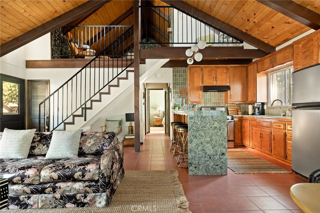 Welcome to the most charming chalet-style dream cabin in Pinewood Estates, Big Bear. This is an incredible opportunity to own the most stylish Big Bear escape, thoughtfully renovated and curated by a Los Angeles interior designer and antique dealer. This 3-bedroom, 2-bath home blends timeless A-frame charm with modern comfort, creating a truly one-of-a-kind retreat. Step inside to soaring A-frame T&G ceilings, a cozy fireplace with wood stove, and a sunny bay window perfect for reading. The beautifully updated kitchen features Cambria quartz countertops with a waterfall peninsula, designer green Zellige backsplash, touchless faucet, and a double-bowl sink—all paired with original vintage cabinetry that adds warmth and character. The loft-style primary suite offers a peaceful retreat with ensuite bath, dual closets, and a large A-frame window framing treetop views. Two downstairs bedrooms include ample storage and vintage dressers, while updated bathrooms showcase modern style with designer finishes. Outdoor living shines with a front deck, fully-fenced backyard, dual-access gates, three producing fruit trees (apple, plum, peach), and a “Dad Pad” converted shed with electric, insulation, and Milgard windows—perfect for a studio, office or game room for the kids. A looped front driveway plus extended driveway and 2-car garage provide ample parking for cars, RV, or boats. Every detail of this home has been thoughtfully upgraded, including: brand new asphalt shingle roof (Malarkey), fresh exterior & interior paint, new flooring throughout, new front & back deck railings and steps, new Therma-Tru Fiber-Classic front door with e-glass, app-controlled locks, Nest thermostat, app-controlled lights, & Eufy security system, new interior stairs and railing, updated window coverings, new USB outlets, new stacked laundry machines, and even a bonus elliptical machine in garage! Located minutes from the lake, ski slopes and village, this home combines designer style, thoughtful upgrades, and mountain charm. Whether you’re seeking a weekend retreat, full-time residence, or investment, this is Big Bear living at its finest. Don't miss this rare opportunity!