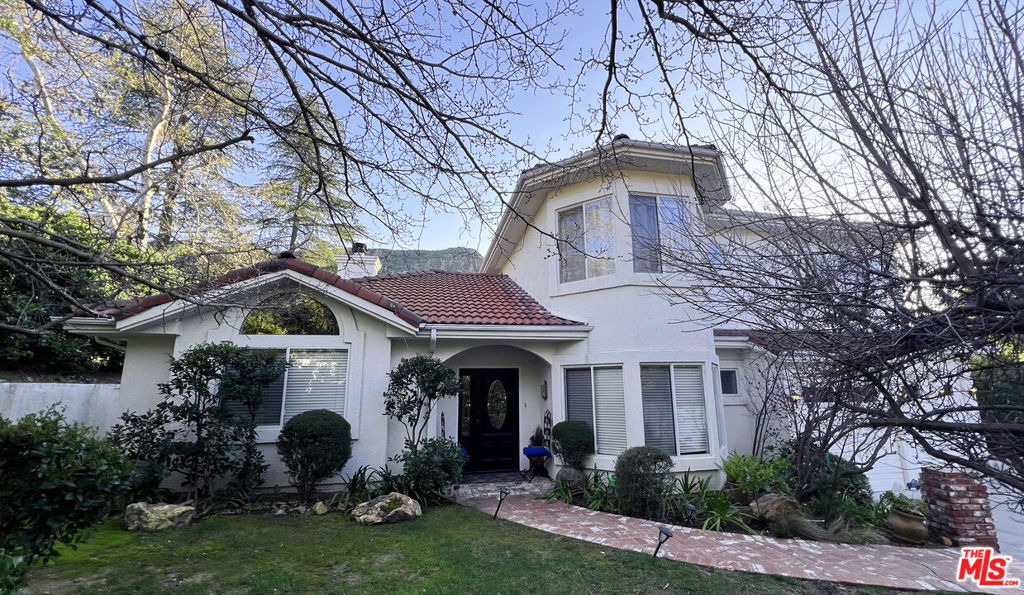 Nestled in one of Agoura Hills most picturesque and storied neighborhoods, this stunning custom residence offers the perfect blend of nature, elegance, and functionality. With sweeping views of the Santa Monica Mountains from nearly every room, this 5-bedroom, 3-bathroom home is a peaceful sanctuary where the indoors and outdoors flow effortlessly. Inside, the light-filled living room boasts soaring vaulted ceilings and a dual-sided fireplace shared with the formal dining room creating a warm, welcoming atmosphere for entertaining or quiet evenings in. The kitchen features granite countertops, a center island, tile floors, and an adjoining breakfast area perfect for morning coffee with a view. The adjacent family room includes another fireplace and sliding glass doors that open to the private backyard, seamlessly connecting indoor and outdoor living. The main level includes a spacious bedroom and full bathroom, ideal for guests or a home office. Upstairs, French doors lead to the expansive primary suite, complete with its own private balcony, updated en-suite bath with a soaking tub, dual vanities, and a separate shower. Three additional bedrooms upstairs provide ample space and flexibility for families or professionals needing room to grow. Step outside to your own slice of paradise: a beautifully landscaped yard filled with mature trees and native plantings, outdoor dining areas, a fire pit, and serene lounging spot - all perfect for relaxing or entertaining while surrounded by nature. Located just minutes from Malibu beaches, the 101 Freeway, and iconic local landmarks such as The Old Place, Cornell Winery, and the Peter Strauss Ranch trails. Here, you'll enjoy the perfect mix of modern comfort, rustic charm, and timeless Agoura Hills heritage. Come experience the magic of mountain living - just a short drive from the city, but a world away.