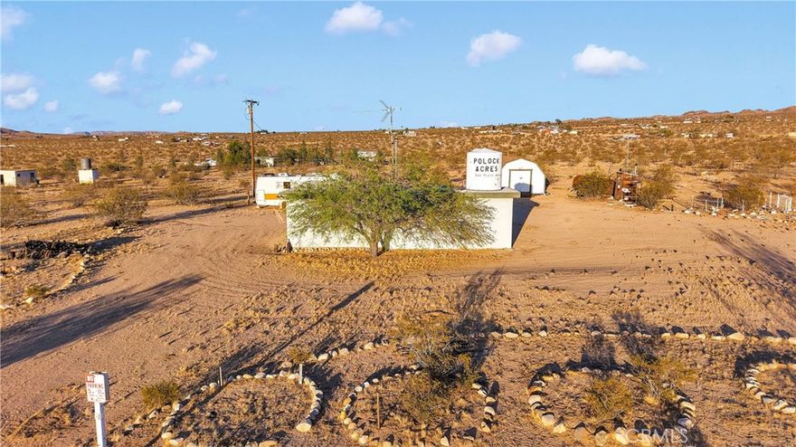 If walls could talk.. the stories this property could tell!! Arriving to this fully fenced 5 acre property on PAVEMENT you will feel like you've taken a step back in time, with so much charm and the feeling of simplicity. The owner purchased this place back before King of the Hammers was a thing and would leave from here and head out that way to go wheeling. They used this property as a place for friends and family to have a spot to camp at (photo attached) and enjoy everything our beautiful desert has to offer. There are multiple RV electrical hook ups in place and 1 motorhome is being left. This original homestead has 1 main building that is approx 400sqft and just an open space with a wall heater and a kitchen that has 2 refrigerators, stove & sink. There is a smaller storage shed next to the house and a larger shed out back. There is also an outhouse (unknown if functioning and unknown hookup). The property has electricity and is on propane.