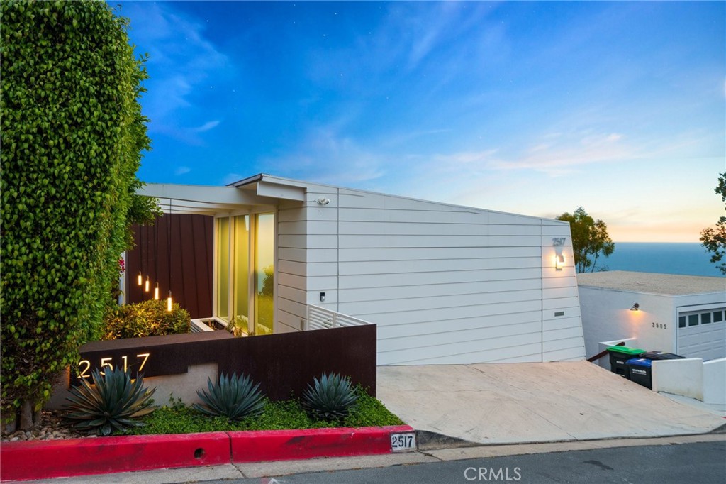 A stunning ocean view showpiece in the heart of Laguna Beach, this architecturally significant residence is a refined expression of modern coastal design. Originally designed by J. Lamont Langworthy & fully reimagined by Laidlaw Schultz Architects in 2019, the home blends timeless craftsmanship with luxury living, offering panoramic ocean, coastline, Catalina Island & sunset views, a highly efficient layout that lives larger than its footprint, & a seamless indoor-outdoor flow. The courtyard is a private sanctuary adorned with cascading planters, bougainvillea, white roses, & an inviting seating area that connects to the main living areas through bifold glass doors-creating a breezy, integrated flow w/sightlines to the water. Beyond the custom steel & glass front door, a striking floating staircase sets the tone for the sophisticated interiors. The open-concept kitchen features bespoke Thometz cabinetry, Neolith counters & waterfall island, & a curated mix of steel, wood, and stone. Smeg & Sub-Zero appliances blend style w/performance, while the kitchen flows effortlessly into dining & living areas, ideal for entertaining against a dramatic coastal backdrop. Walls of bifold & multi-slide glass doors open to a coastline view deck with frameless glass railings, enhancing the home's indoor-outdoor lifestyle. Lower level primary suite is anchored by a board-formed concrete feature wall & includes oversized sliding doors to a private patio, European-style closets, and a spa-inspired bath with Neolith surfaces, stone flooring, & serene ocean views. Adjacent is a flexible space perfect for a gym, dressing room, or walk-in closet. The loft functions as a dramatic ocean view third bedroom & additional living space, showcasing a dramatic steel-framed entry, sliding window system, custom built-ins, & a stunning full bath with stone & quartz finishes. A separate casita suite with ocean views and walls of windows adds versatility, ideal as a guest retreat, creative studio, or executive office. Additional features include wide-plank oak and stone flooring, Kolbe & Kolbe Vista Luxe windows, owned Tesla solar with battery backup, automatic shades, 3-zone HVAC, & a Corten steel roof & gutter system. This is not just a home, it’s a modern coastal sanctuary where design, light, and landscape converge. From its meticulously curated materials to its breathtaking vantage points, this residence offers an elevated living experience in one of Laguna Beach’s most iconic settings.