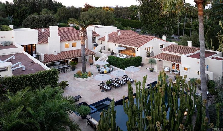 Quintessential Southern California  Nestled within the prestigious enclave of the Rancho Santa Fe Covenant, 6977 Las Colinas stands as a timeless homage to early California hacienda architecture. Inspired by the grace of 1920s Montecito, this three-acre estate embodies the serenity and mission-style beauty that define Southern California’s heritage. Native palms, olive and lemon trees, lavender, and white roses create a landscape as natural as it is refined.  Behind a hand-forged 18th-century Mexican door, warmth and authenticity unfold. A beamed portico with a fireplace opens to a courtyard alive with greenery, a vintage fountain, and softly glowing lanterns. Inside, reclaimed wood floors, carved beams, plaster archways, and antique Mexican doors connect luminous rooms and sun-drenched terraces.  Recently restored, the home balances heritage with modern livability. Remodeled baths, updated systems, and the careful restoration of original ironwork and finishes honor its “Old Soul” while revealing a “Young Heart.” The interiors evoke the relaxed refinement of a boutique hotel—elegant yet unpretentious, where every detail feels intentional.  Expansive terraces, a heated pool and spa, an outdoor kitchen, and a sport court celebrate the indoor-outdoor lifestyle. Set along a tree-lined Covenant road, this private retreat is minutes from the Village and the historic Inn at Rancho Santa Fe. Covenant ownership includes immediate membership eligibility to the Rancho Santa Fe Golf & Tennis Club—no waitlist or sponsorship required.