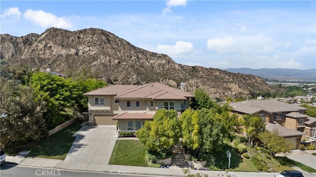 Welcome to this stunning view home in Southern Oaks, complete with a sparkling pool, entertainer’s backyard, and a prime hilltop location in one of Santa Clarita’s most cherished neighborhoods. With lush landscaping already in place and thoughtful upgrades throughout, this home offers so much! Inside, you’ll find four bedrooms, a spacious loft, and a flexible bonus room off the primary suite that works beautifully as a home office, gym, nursery, or private retreat. A full bedroom and bathroom on the first floor adds convenience for guests or multigenerational living. The open kitchen features a large center island, granite countertops, updated cabinetry, walk-in pantry, and built-in Thermador Subzero refrigerator. It flows seamlessly into the family room and connects to the formal dining and living areas, making entertaining easy and everyday living comfortable. Additional highlights include hardwood flooring, a modern wrought iron staircase, dual HVAC systems, wireless/keyless garage entry, fresh interior and exterior paint, and an extended driveway with plenty of parking. Out in the back, the saltwater pool and spa, rebuilt in 2016, are surrounded by an outdoor kitchen equipped with a built-in BBQ with granite counters, outdoor fridges, a sink, a cozy fireplace, the beautiful covered patio, and peaceful hillside views. You'll love this established community with mature landscaping, tree-lined streets, and the long-standing, top-rated schools nearby. The HOA also includes a community pool, spa, and clubhouse. It’s a wonderful home in a true gem of a neighborhood—offering the space, character, and convenience that buyers are looking for today!
