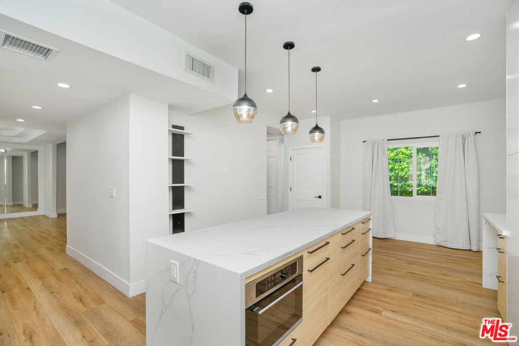 Stunningly remodeled tri-level condo in the heart of Tarzana offering 3 bedrooms, 3.5 baths, and over 2,100 sq. ft. of beautifully reimagined living space. Every detail has been thoughtfully upgraded, showcasing wide-plank flooring, recessed lighting, modern steel railings, and a bright open-concept design. The chef's kitchen is a true showpiece, fully remodeled with custom European cabinetry, a marble waterfall island, and sleek designer fixtures. Each bedroom features its own spa-like en suite, while the primary suite impresses with a marble fireplace, private balcony, walk-in closet, and a luxurious bath with dual vanities, soaking tub, glass-enclosed shower, and heated toilet. Additional highlights include dramatic dining and living areas with statement fireplaces, an expansive rooftop deck for outdoor entertaining, and a private two-car garage with epoxy flooring and ample storage. Perfectly situated near the 101, Providence Cedars-Sinai Tarzana Medical Center, scenic hiking trails, and Tarzana's best shopping and dining. A rare opportunity to own a fully remodeled, sophisticated retreat in one of the Valley's most sought-after communities.