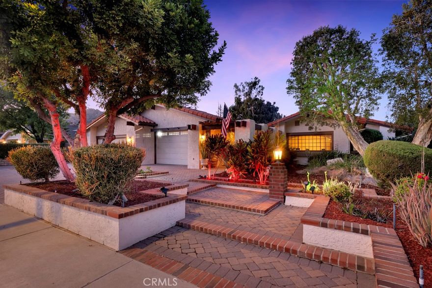 Welcome to a truly special Chatsworth residence that blends timeless character with thoughtful modern enhancements. Nestled in one of Chatsworth’s most sought-after enclaves where homes rarely come to market, this 5-bedroom, 4-bath property offers nearly 3,500 sq ft of living space on an expansive 0.40-acre lot. Meticulously cared for and upgraded with quality materials, key features include a US tile terracotta ceramic roof and refinished antique Saltillo tile flooring (2025), plus a dual-zone HVAC system with major updates—one zone fully replaced in 2023. All exterior and interior walls are insulated, a rare feature ensuring year-round comfort and efficiency. The exterior was refreshed in 2022 when the entire home was painted with Ceramic Shield paint. The front of the home showcases manicured landscaping, a large gated driveway with RV potential, and a 4-car garage with overhead storage. A gated entry leads through a colonnade to a peaceful courtyard and a refinished vintage fountain. Through the front door, you’re welcomed by a step-down living room with vaulted ceilings, a fireplace, and large patio doors opening to the backyard. The west wing includes a spacious great room with new carpet, vaulted ceilings, a fireplace, a wet bar, built-ins, and abundant natural light. The kitchen has been almost entirely rebuilt with newer appliances, a large granite center island with a sink, plenty of cabinetry, a breakfast area, sliding door access to a side patio, and a formal dining room. This wing also features a generous bedroom with courtyard access—ideal as guest quarters, studio, or office—plus a renovated hallway bathroom and large laundry room with built-in storage. In the east wing, the primary suite offers vaulted ceilings, sliding door access to the backyard, a walk-in closet, and an ensuite bathroom. Two additional hallway bathrooms are large in size and serve the remaining three guest bedrooms, which offer ample space and storage, including one by the courtyard with refinished parquet flooring—perfect for a home office. The backyard offers a large pool, multiple patios, and lush landscaping surrounded by six mature citrus trees—two Navel orange, two Valencia orange, one Meyer lemon, and one kumquat. Don’t miss this rare opportunity to own a one-of-a-kind home in Chatsworth—minutes from hiking trails, parks, and mountain views.