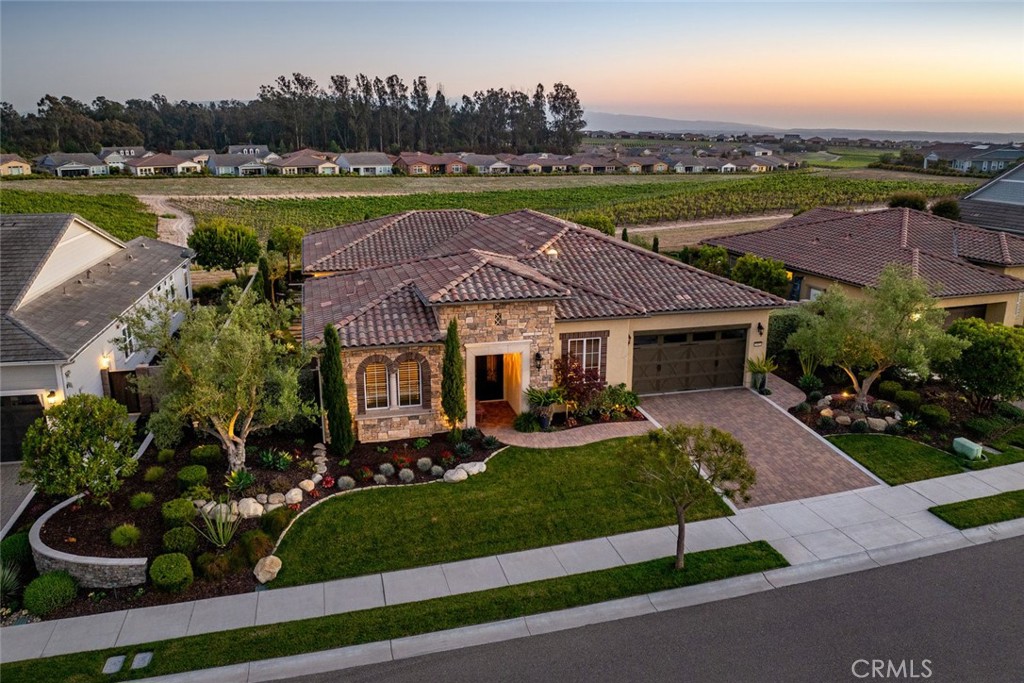 A taste Of Italy, situated in an elevated premium location in Trilogy, this “custom” Avila model features over $500,000 in upgrades. This 2,638 sqft. residence provides open-plan living/entertaining space with inter-connected living room, dining room, 2/3 bedrooms, 2 full baths, powder room, flexible bonus room and office/ den. A key feature that sets this home apart is the unique extra-large 641 sqft, fully-appointed outdoor California room bringing the total living space of this residence to 3279 sqft. Step through the tiled Portico entrance with striking double iron doors, and you’ll discover engineered wood flooring, Knotty Alder solid core doors/baseboards plus window sills/aprons. You’ll love the fully-appointed true chef’s kitchen with a large granite top island (for prep, dining or entertaining), loads of counter prep space, KitchenAid stainless appliances including double wall ovens and 36” Pro 6-burner range top, Travertine stone backsplash with artist-designed medallion accents, extensive raised panel cabinetry with upper display glass doors and handy lower cabinet roll-out shelves, wine cooler, microwave, custom pendant lights, solar tubes with LED solar powered nite lights, and a large walk-in pantry. The light and airy living room with its cozy fireplace and spectacular 4-panel rolling wall of glass opens to the sweeping rear vineyard view. Unique to this home, is a 641 s/f covered California room featuring a custom stacked stone gas fireplace with hearth, porcelain tile floors and 3 power screens overlooking a striking custom water feature, meandering flagstone paths, lush landscaping with mature trees and ambient accent lighting surrounding the residence. In the evenings, your vineyard view master suite awaits – a large bedroom with a dedicated sitting area, his and her fully-customized walk-in closets, a stunning master bath w/soaking tub, tiled shower with vineyard view and seamless glass enclosure, dual vanities with quartz counter tops and framed mirrors. An adjoining room offers possibilities as a private office, exercise spa, art studio or bedroom. On the other side of the home, overnight guests will enjoy a large private bedroom en-suite bath with shower/tub. Additionally, there’s a den/office with French door enclosure (possible 3rd bedroom), SmartSpace laundry with sink, abundant storage, linen closet & built-in desk, plus a convenient powder room with custom sink/vanity and crown molding. A/C and SOLAR are, of course, included.