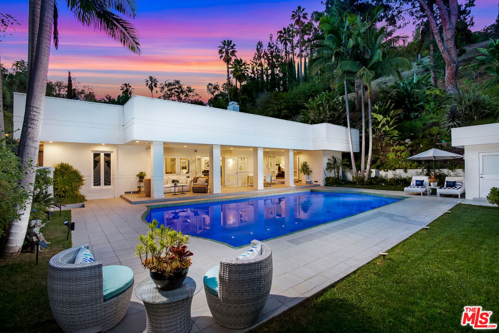 Fully furnished and available for short or long-term stays, this stunning contemporary estate is nestled in prime Beverly Hills, offering the perfect blend of luxury, privacy, and proximityjust minutes from Rodeo Drive. Set on resort-style grounds, the home features a dramatic open floor plan with 14-foot ceilings, skylights, and new designer ombre grey wood floors throughout. The main level includes a spacious primary suite that opens to the outdoors, complete with dual bathrooms and dual walk-in closets. A grand great room with wet bar, formal dining area, and entertainer's kitchen complete the flow. An additional room on the first floor serves as an ideal office or fifth bedroom. Upstairs, you'll find three more bedrooms, one and a half bathrooms, and a comfortable lounge area. The lushly landscaped backyard is surrounded by mature palm trees and features a sparkling pool, making this home the ultimate private retreat for entertaining and relaxation.