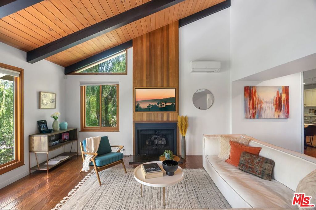 Discover this peaceful and beautifully updated home located in the quiet hills of Woodland Hills. A covered front patio leads to a step-down living room with vaulted, beamed ceilings, a striking floor-to-ceiling fireplace, and large windows overlooking mature trees. The modern kitchen includes quartz countertops, updated appliances, and wood flooring, with French doors that open to a covered patio, perfect for dining and entertaining outdoors. The lower level features a spacious office and a newly remodeled bathroom with quartz counters, glass elements, and decorative tile. Upstairs, the primary suite offers a tranquil, cabin-like feel with high ceilings and large windows. The ensuite bath includes a skylight-lit glass shower, quartz counters, and custom cabinetry. Step out to a Zen-inspired backyard with a spa, waterfall, and peaceful patio space. The home also includes a second upstairs bedroom, beautifully landscaped gardens with multiple sitting areas, and scenic views from most rooms. A two-car garage, covered parking with gated entry, new HVAC system, ductless A/C unit, and upgraded windows complete this move-in-ready home. Great income potential with newly built ADU with separate entrance and address! Don't miss the best value in Woodland Hills