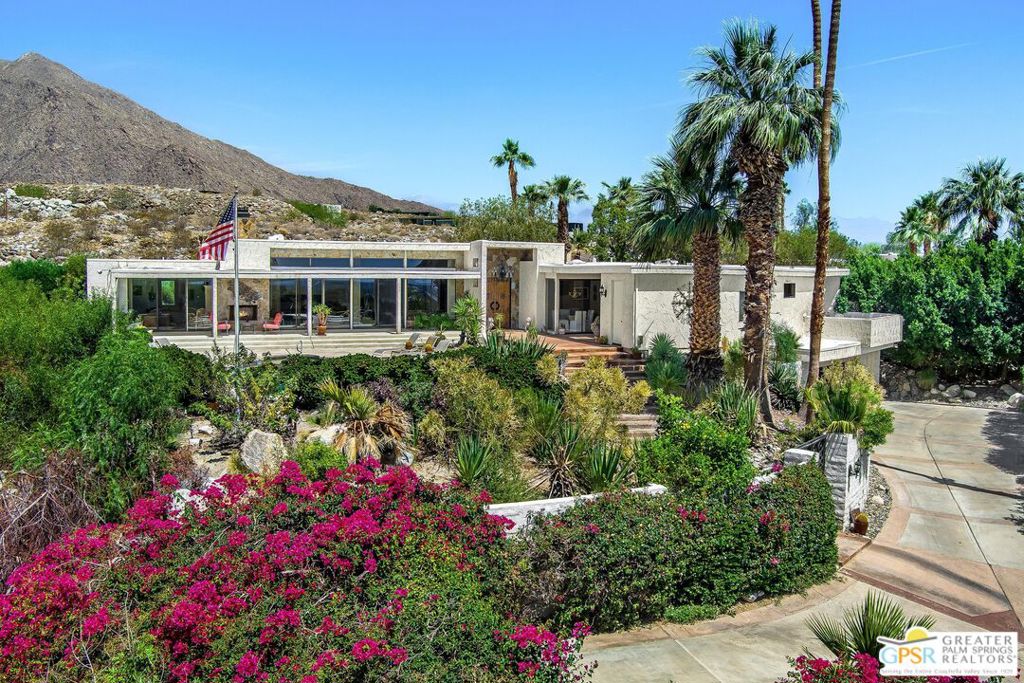 Perched high above Palm Springs in the sought-after Little Tuscany neighborhood, this striking example of modernist architecture offers a rare blend of privacy, scale, and breathtaking "top of the world" views. Masterfully sited to capture sweeping 360 degree vistas of the valley floor, desert expanse, and Mount San Jacinto, the home reflects the natural drama of the landscape itself. The hillside ascent builds quiet anticipation, culminating in an entry that reveals a sweeping desert panorama in unforgettable fashion. Conceived at the height of desert modernism and retaining original interior elements by legendary Palm Springs designer Steve Chase, the residence channels a spirit of casual California elegance. Its nearly 5,400 square feet of living space is thoughtfully balanced, offering both grand entertaining areas and tranquil retreats. The pool terrace invites both leisurely afternoons in the sun and elegant evenings under desert skies. Additional features include a dedicated wine room, sauna, gallery-style architectural details, and original vein-cut honed travertine floors that lend a timeless, desert-appropriate elegance throughout. Thoughtfully landscaped with mature palms, blooming bougainvillea, and sculptural cacti, the landscaping offers a vibrant counterpoint to the home's clean lines, layering texture and color into the hillside setting. Elevated in every sense, this residence redefines what it means to live above it all.