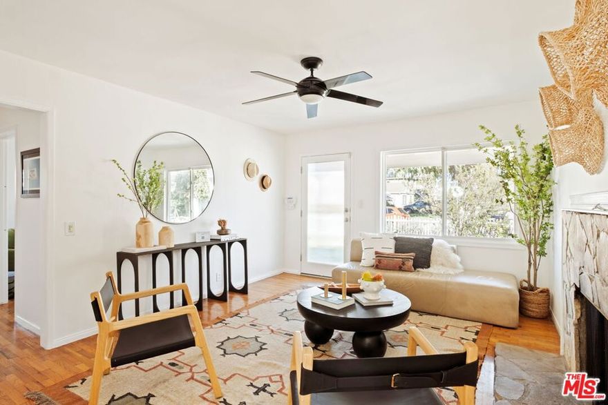 A storybook white picket fence and leafy trees welcome you to this enchanting home on one of Mar Vista's most beloved streets, 3379 Stewart Avenue. From the moment you step onto the inviting front porch, you'll feel the warmth and ease of a true neighborhood gem, where the pace slows and the sense of community shines. Inside, natural light pours through oversized windows, dancing across rich wood floors and filling the living room with an effortless glow. Gather around the classic fireplace or enjoy the seamless flow into the thoughtfully designed kitchen, complete with custom cabinetry, stone counters, and a built-in corner dining nook perfect for morning coffee or cozy dinners. This three-bedroom, two-bath residence offers comfort and character in equal measure. French doors from the primary bedroom open to a whimsical, sun-dappled backyard a private haven for relaxation or lively weekend entertaining. Whether it's quiet evenings under the string lights or brunch with friends, this space was made for moments that linger. A detached garage adds versatility and potential ideal for a creative studio, home gym, or future ADU. With its idyllic curb appeal, timeless charm, and proximity to Mar Vista's parks, local cafes, and vibrant community, this home captures the essence of Westside living at its most welcoming.