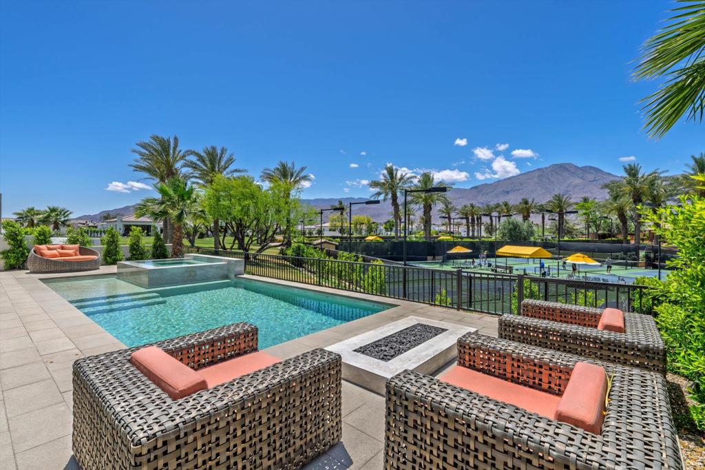 Experience the essence of desert luxury in this beautifully upgraded 3-bedroom, 3.5-bath Villa at Andalusia Country Club, complete with a private detached casita and ideally positioned on a premium lot near the clubhouse. Showcasing 180-degree views of the Santa Rosa and Coral Mountains, this 2,634 square-foot home blends sophisticated desert contemporary design with an open-concept layout and seamless indoor-outdoor living. Thoughtful upgrades include oversized porcelain tile flooring, custom designer lighting, motorized shades, a striking floor-to-ceiling fireplace, and expansive glass pocket doors that open to a covered loggia with recessed heaters and a built-in BBQ. The chef's kitchen features a granite waterfall island, sleek self-closing cabinetry, custom tile backsplash, and high-end stainless steel appliances. An adjacent custom bar with seating for eight creates the ultimate space for gathering. Wake up to breathtaking mountain views from the serene primary suite, complete with dual vanities, a spacious glass-enclosed shower, and a custom walk-in closet. Step outside to relax in the custom pool and spa, or gather by the firepit to watch the sun set behind the mountains. Additional highlights include an owned solar system, whole-home water softener and conditioner, gas and water auto shut-off valves, and epoxy-coated garage floors. Come live the life you've always imagined!