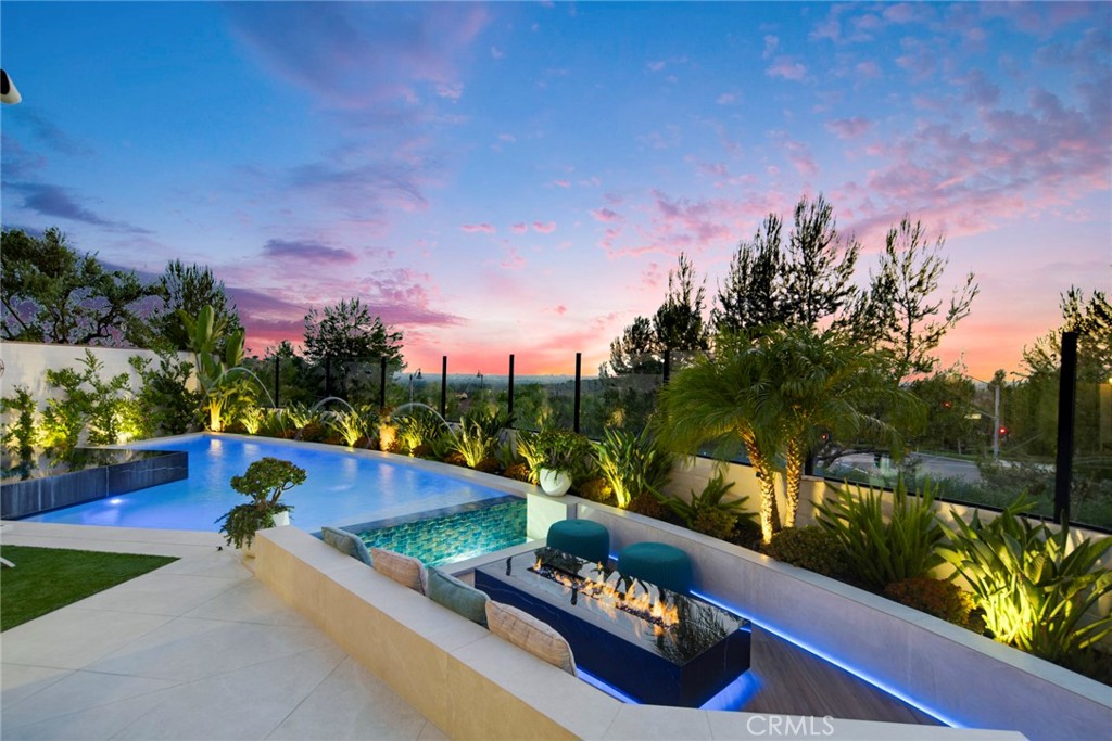 RARE – Private Luxury City View Lot with Custom Infinity Pool, Spa, in Orchard Hills
Discover rare privacy, luxurious upgrades, and panoramic views in this exceptional home located in The Reserve at Orchard Hills, an exclusive 24-hour guard-gated community in Irvine. With over $300,000 invested in a one-of-a-kind backyard retreat, this home delivers the ultimate Southern California lifestyle.
This exquisitely upgraded 3-bedroom, 2.5-bathroom residence spans a premium lot with unobstructed views of city lights, rolling hills, and Catalina Island on a clear day. The expansive resort-style backyard features a custom pool with a stunning infinity waterfall edge, a raised spa, and custom LED lighting throughout. A large seating area with an elongated fire pit, built-in BBQ island, and standing bar with integrated fire feature makes this an entertainer’s dream. A tranquil water fountain and remote-controlled patio cover complete the space, offering total relaxation and year-round enjoyment.
Inside, the home offers a seamless blend of elegance and functionality. The chef’s kitchen is fitted with quartzite and quartz countertops, custom cabinetry, and a stylish chandelier, flowing into a spacious great room with bespoke built-ins and expansive stacking glass doors that open to the backyard for perfect indoor-outdoor living.
Upstairs, the primary suite offers a serene retreat with a walk-in closet and spa-inspired bath featuring a marble-surround soaking tub, walk-in shower, private water closet, and dual sinks. The additional bedrooms are generously sized and share a full bathroom with quartz countertops and dual sinks.
Sustainability meets convenience with a fully owned solar panel system and two Tesla Powerwalls, dramatically reducing energy costs—your electricity bills are nearly nothing while enjoying seamless backup power and energy efficiency.
Residents of The Reserve enjoy exclusive access to luxury amenities including a resort-style pool and spa, clubhouse, scenic parks, and miles of hiking and biking trails. Located near top-rated schools like Northwood High, and just minutes from upscale shopping, dining, and major freeways, this impeccably maintained home offers an unmatched combination of privacy, sustainability, elegance, and lifestyle convenience in one of Irvine’s most coveted communities.