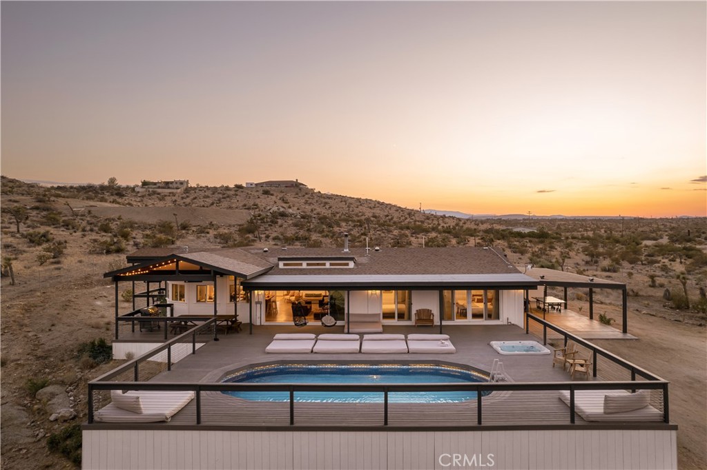 Cloud Canyon: A hidden gem in the rugged beauty of Joshua Tree’s High Desert, where boulder-strewn landscapes meet modern desert luxury. Set on an irreplaceable lot on a coveted street, this 4-bedroom, 2-bathroom sanctuary offers access to thousands of acres of untouched hikeable land, a rare retreat for those seeking both adventure and tranquility. With over 3,000 square feet of outdoor living space, Cloud Canyon captivates at every turn. This isn’t just a home—it’s a high-end escape into nature’s serenity. Host unforgettable gatherings framed by iconic boulders, lounge by the oval pool, or soak in the hot tub under a sky of stars. A regulation-size pickleball court, dual basketball rims, and a fire pit for stargazing make the outdoor experience extraordinary. Each room opens to its private deck, blending indoor comfort with the natural landscape. As the sun sets, built-in string lighting adds a magical glow, making every evening special. Step inside, and the elegance continues. Cloud Canyon is as luxurious as it is inviting, featuring seven plush beds for guests, while the expansive master suite offers serene views and a private escape with direct poolside access. The open-plan kitchen, dining, and living areas are bathed in natural light creating a seamless connection with the outdoors. Every intentional detail elevates your living experience with sophistication and style. Cloud Canyon has earned “Guest Favorite” status on Airbnb, maintaining a 5-star rating and strong income potential. From all-new windows and modern AC systems to high-end custom furnishings and new insulation, no detail is overlooked. Sustainability is key, with owned solar panels and an EV charging system providing eco-friendly luxury. A covered carport with recessed lighting adds further convenience to this retreat. The magic of Cloud Canyon lies not just in its features but in the lifestyle it offers. Tucked away in its own corner yet minutes from Joshua Tree National Park and Pioneertown, it blends privacy, exclusivity, and desert serenity. Whether exploring private trails, hosting gatherings, or unwinding by the fire pit under a sea of stars, Cloud Canyon delivers an unparalleled High Desert experience. This property isn’t just rare—it’s a one-of-a-kind sanctuary. Cloud Canyon embodies everything magical about Joshua Tree, offering a lifestyle of pure luxury and relaxation. Here, every moment feels special, and every detail speaks to those who seek the best of desert living