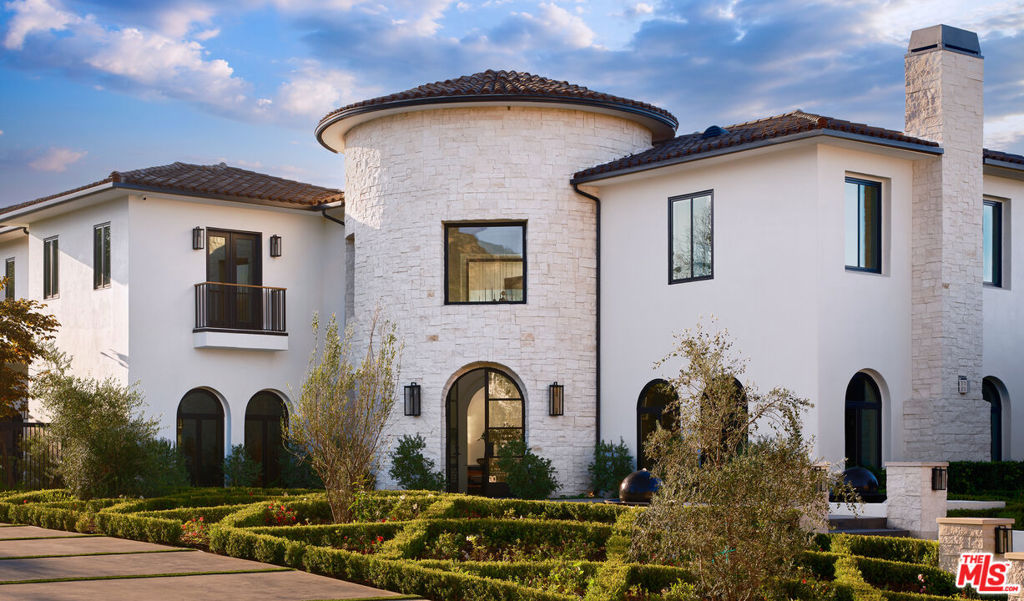 Tucked behind double security gates within the esteemed Estates at The Oaks, this exceptional residence spans approximately 15,000 square feet across more than an acre of privately gated grounds. Set near the end of a quiet cul-de-sac, the approach introduces soaring 30-foot ceilings and an open-air interior courtyard, immediately establishing the home's scale, serenity, and seamless connection to the outdoors. Expansive living spaces are drenched in natural light from grand arched windows and floor-to-ceiling glass doors. Oak floors with herringbone accents run throughout, anchoring a layout that balances volume with warmth. A formal dining room with coffered ceilings opens to an alfresco terrace with fireplace, while a sunken fireside lounge near the pool offers a one-of-a-kind entertaining moment. Additional amenities include a fully equipped home theater, a dedicated gym with sauna, a custom office, and a striking wine display and tasting lounge enclosed in glass. The heart of the home is a newly designed chef's kitchen appointed with top-tier appliances, a spacious breakfast area, oversized butler's pantry, and separate caterer's kitchen all oriented to flow into the family room, where sliding glass walls frame garden views and a dramatic full-height fireplace. Seven total bedrooms and nine bathrooms include six private suites within the main house, each with a newly appointed bath. The primary retreat enjoys panoramic mountain views, a fireplace, and a private terrace, accompanied by dual custom closets and a spa-like bath with a glass-wrapped shower, soaking tub, and separate water closets.A newly constructed guest house mirrors the quality and detail of the main home, complete with a full kitchen, den, fireplace, and sliding glass walls that open to a covered lounge. Outside, every inch of the grounds has been carefully considered: a sparkling pool with waterfalls and LED lighting, custom half basketball court, putting green, expansive turf lawn, and garages for four cars behind a second set of gates. Located in one of Calabasas' most coveted guard-gated enclaves, just moments from acclaimed schools, shopping, and the beaches of Malibu, this residence offers both elevated design and enduring comfort a rare combination in one of Southern California's most desirable communities.
