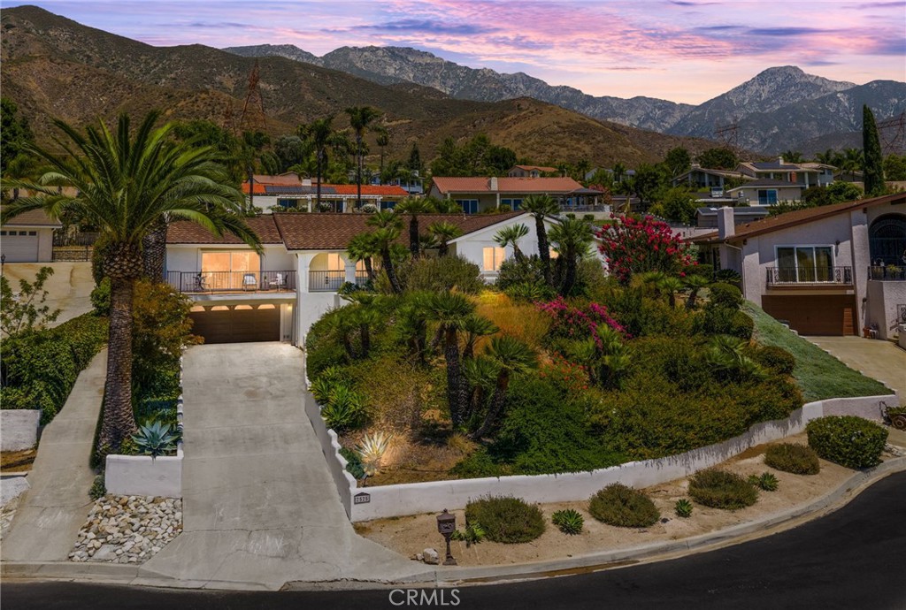 Where the charm of Santa Barbara meets the heart of Upland. Welcome to a one-of-a-kind retreat in the foothills of San Antonio Heights. Tucked at the end of a quiet cul-de-sac, this 4-bedroom, 3-bath home is full of soul, style, and standout scenery. Arched entryways, terracotta tile, and custom finishes set a warm, timeless tone, while the lush landscaping and postcard-worthy mountain views make every day feel like a getaway. Step inside to light-filled living spaces that blend elegance and comfort. The formal living room is ideal for music, conversation, or simply soaking in the peaceful front porch views. Around the corner, a spacious family room invites you to unwind with vaulted ceilings, exposed beams, and custom built-ins that add both character and functionality. At the heart of the home, the upgraded kitchen offers stone countertops, stainless steel appliances, and ample cabinetry, perfect for hosting or quiet nights in. But it’s the outdoor space that truly captures the magic. From coffee with the mountains to poolside afternoons and starlit evenings, the backyard feels like a private resort. Surrounded by mature palms and curated landscaping, it’s a setting designed for year-round enjoyment and effortless entertaining. Additional highlights include dual-pane windows, an indoor laundry room with utility sink, generous storage, and a 1/4 share of valuable local water stock. If you’ve been waiting for something special with serenity and Santa Barbara-inspired style, this is the one.