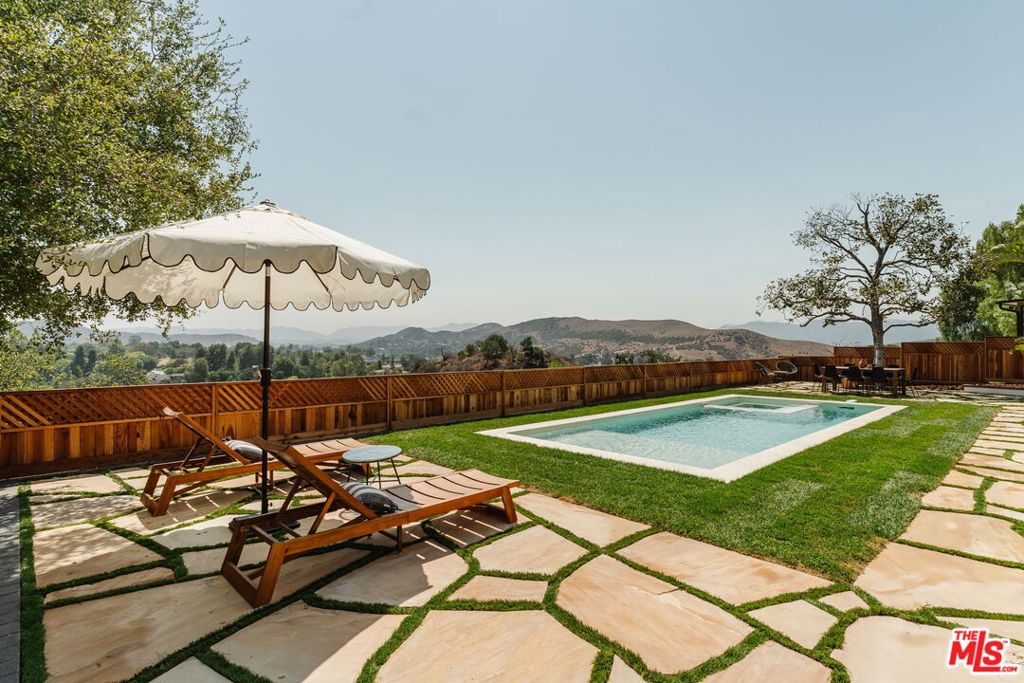 Welcome to The Magnolia House, a breathtaking modern Spanish-style view home at the end of a quiet cul-de-sac in Agoura Hills' coveted Hillrise neighborhood. A true unicorn with magazine-worthy design, this one-of-a-kind home commands unobstructed views of Old Agoura, Chumash Park, and the Santa Monica Mountains--all while offering a seamless indoor-outdoor lifestyle. With exceptional curb appeal, this practically brand-new two-story residence features new hardscape pathways + driveway, a striking walnut garage door, El Dorado smooth stucco finish, and lush Mediterranean landscaping. Step into the airy foyer where white oak hardwood floors and soaring 20ft ceilings set the tone, but what truly defines the experience is the home's rare explosive views from nearly every room, captivating you the moment you step inside. The open floor plan is framed by 12ft sliders and picture windows. A dramatic gas fireplace with built-ins anchor the living area, while the dining space flows seamlessly into the chef's kitchen, a showpiece with 10ft island, Pietra Grey Cesar Stone counters, custom cabinetry, open shelving with integrated exhaust hood, designer lighting and hardware, luxury KitchenAid and LG appliances, and gold-patinated fixtures--the jewels of the home. Upstairs, the primary suite boasts sweeping mountain views, dual closets, and a spa-like bath with freestanding soaking tub, glass-enclosed shower with earthy stone, chrome finishes and a custom white oak dual-sink vanity. Two large additional bedrooms enjoy Magnolia tree and sunset views complimented by a full designer bath. A flexible fourth bedroom downstairs is ideal for family or guests and offers additional space for a home office, with an adjacent designer bath and separate laundry closet and storage. With east-facing views, mornings begin with glorious sunrises as rooms open effortlessly to the expansive backyard. Here, European-style flagstone, a fresh grassy yard, and a brand new 30ft pool with spa and baja shelf create the ultimate lifestyle. Multiple seating areas invite relaxation, with Al' fresco dining beneath the vibrant Magnolia tree to quiet moments soaking in the unobstructed views from sunrise to sunset. The expansive lot also offers an additional 500 sf area perfect for creating a sustainable garden--making this a private outdoor oasis few properties can match. This home has undergone an extensive renovation down to the studs valuing over $500,000 in upgrades with brand-new plumbing, HVAC, tankless water heater, drainage, copper plumbing, new pool/spa, smooth stucco, gutters, windows, doors, sod, landscaping w/ automatic irrigation, low voltage wiring, 300 linear feet of brand new wood fencing, flagstone w/ pea gravel, walnut garage door with automatic lift gate, and 200amp electrical panel ready for an EV charger or solar installation. The garage is fully finished with drywall, vaulted ceilings, recessed lighting, and epoxy floors and the roof is only a few years old. Perfectly suited for those who yearn for a true suburban lifestyle while still enjoying the amenities and conveniences of the city, Agoura Hills is a community built on connection, family, and an appreciation for the outdoors. This coveted neighborhood offers top-rated public schools and, while only 30 minutes from Los Angeles, is moments to Calabasas, Westlake Village, and Malibu's Cross Creek, just a scenic 20-minute canyon drive away. A hidden gem, Agoura delivers stately properties and an elevated quality of life without the premium price tag of its neighboring cities, blending beauty, convenience, and value in one extraordinary offering. Do not miss this opportunity. Offers due Monday, August 25th at noon.