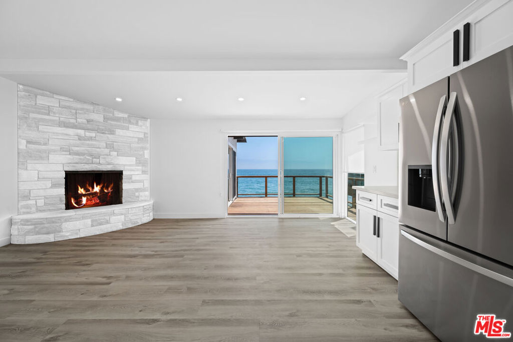 Charming Beach Cottage on Malibu Road. Step into the Malibu lifestyle with this updated and inviting beach cottage, situated in an intimate four-unit building on iconic Malibu Road. Bursting with charm and coastal character, this home offers the ideal blend of comfort, style, and seaside serenity. Inside, you'll find an open-concept layout with wood floors, recessed lighting, and a cozy fireplace that sets the tone for relaxed beachside living. The remodeled kitchen features sleek new appliances and generous counter space-ready for everything from casual breakfasts to sunset dinners. Both bedrooms have updated bathrooms. Step outside to your private oceanfront deck- the perfect place to sip your morning coffee, enjoy an al fresco meal, or unwind to the sound of the waves. Additional features include air conditioning, a one car garage with an additional parking space, and direct beach access just steps from your door. Shared laundry is located on the side of the building. Located on one of Malibu's most desirable streets, this is your chance to enjoy peaceful coastal living with easy access to the best of Malibu's dining, shopping, and natural beauty.