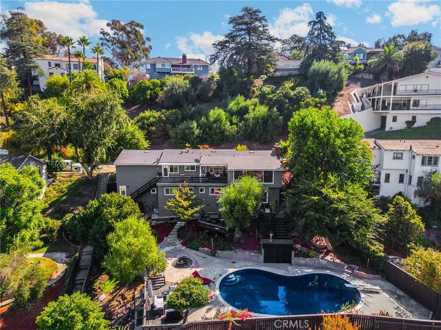 Spectacular LOCATION in the prestigious and exclusive College Hills neighborhood. This is a locals-only-known community of elegant vintage and historical homes that are adjacent to the "Western Ivy League" campus of Whittier College. This is a friendly neighborhood where most homes are held by families for decades and rarely come up for sale. The views from every window offer vistas over the quiet, verdant neighborhood and of glorious tall pine trees. This home has gorgeous hardwood flooring and beautiful natural light through large picture windows. The popular open concept floorplan allows family and friends to gather in the living room, den, and dining room with ease and then pack into the kitchen for intimate conversation at the kitchen counter chairs. The kitchen and bathrooms have been renovated and the house enjoys many updates all while keeping the integrity of the architectural style. All of the bedrooms are downstairs where peace and quiet are revered: the Primary suite (with MASSIVE walk-in closet) is at one end of the hall, two large bedrooms and hall bathroom are in the middle of the hall and the Jr. Suite (perfect for teen/college/in-laws) is at the other end of the hall. The rear decks, garden and pool area are the ultimate and most exquisite spaces for entertainment. You will love the many seating areas- both spacious and intimate- for parties that can accommodate large or small gatherings. The luxurious black bottom pool is heated which allows year-round swimming along with numerous patio areas for sunbathing. Dog lovers will delight in having an enclosed area where Fido can run wild without feeling caged-in. This home also features a beautiful room with a Dutch-door to the exterior that would make a marvelous artist's studio, exercise room, workshop or "Costco room". Historical Uptown Whittier is a short stroll away and offers a vibrant community of restaurants, breweries, shops & entertainment and the Ruth B. Shannon Center for the Performing Arts is down the street and features first-rate theatre and musical performances and Whittier College access to sporting events & venues for everyone to enjoy. There are nearby access points to Worsham Canyon which is an excellent hiking/mountain biking entrance to The Puente Hills Habitat Preservation Authority which manages nearly 4,000 acres of protected lands. Visit https://www.hillsforeveryone.org/visitors-guide/puente-hills-preserve/access/ and https://www.habitatauthority.org/#trailheads