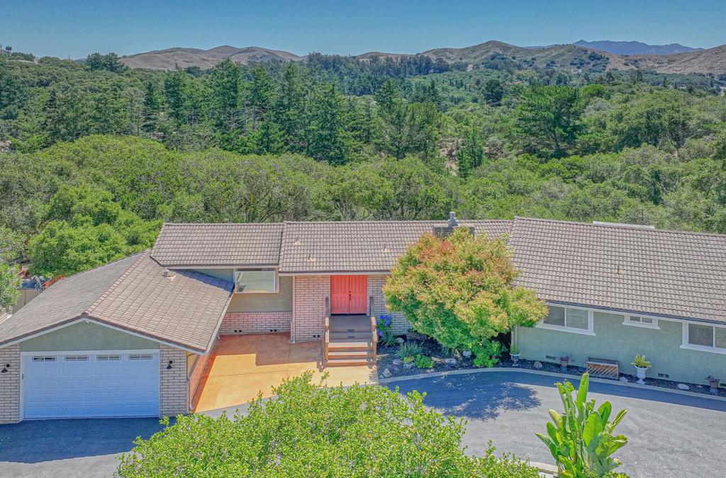 A private one-acre retreat designed for comfort and entertaining. Fully fenced and beautifully landscaped with lighting, stone pathways, a waterfall, a koi pond, and mountain views. The expansive outdoor living area features a Premium kitchen with a wet bar, multi-level patio, multiple seating areas, and large patio area next to outdoor kitchen. Truly an entertainer's dream. Sliding doors from the kitchen, living room, primary suite, and office/sitting area open to a full-length deck with a hot tub to enjoy the serene views. Inside, the open-concept kitchen boasts a Wolf range, Sub-Zero refrigerator, Bosch convection/microwave oven, granite countertops, custom wood cabinets, and a large pantry. The living room offers a cozy fireplace with insert. Additional amenities include a detached finished artist studio/office/workout room, back-up generator, whole-house A/C unit, tankless water heater, exterior security camera system, electric privacy gate, chicken coop, circular driveway with fountain, RV/guest parking, car wash area, and several outbuildings for extra storage. A truly unique property that must be seen to appreciate the quality and attention to detail throughout.