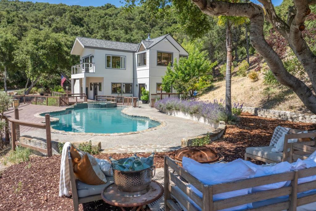 Carmel Valley Retreat with Pool, Pond & Panoramic Valley Views. Experience complete privacy in the coveted Los Tulares community of Carmel Valley. This spacious 4-bedroom, 3.5-bath, 3,365 sq. ft. home sits on 2.2 acres of open meadow, backing to the expansive 2,500-acre Wilson Ranch. Enjoy stunning views of rolling green hills, meadow, olive trees, gardens and your own seasonal pond. The home features a spacious kitchen with quartz countertops and an island, flowing into a formal dining room. The living room features high, open beam ceilings that enhance the light airy feel. The primary bedroom has its own private entrance with a loft above, plus plenty of storage throughout the home. Comfort is ensured with air conditioning, and central forced air heat. Outside, relax by the heated pool and spa, soaking up the sun in total privacy. A workshop and ample space provide plenty of room for oversized vehicles, along with a dedicated dog run and open meadow areas. Just minutes from town, this is the ultimate Carmel Valley retreat.