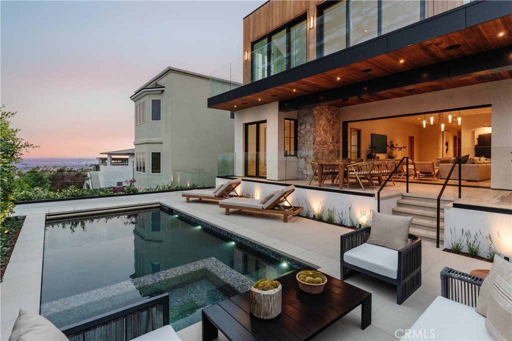 Nestled in the coveted Hill Section of Manhattan Beach, 876 5th Street is a timeless retreat set on a one-of-a-kind lot, offering some of the most breathtaking views in the neighborhood. Completely renovated, nearly every element of this home has been thoughtfully reimagined. With 5 bedrooms + an office, 7 bathrooms, and a thoughtful reverse floorplan, the home offers a rare mix of generous scale and understated elegance. Perched at one of the highest points in the Hill Section, its elevated layout maximizes the sweeping ocean views from the Palos Verdes Peninsula and Catalina to Malibu. Entering through the custom pivot front door, you are welcomed into the main level of the home featuring three bedrooms, each with an ensuite bath, and a versatile home office that may also function as an additional bedroom. Additionally on this level, a spacious den/family room with a built-in wet bar, opens directly to the backyard terrace and pool deck. Outside, a covered dining terrace with built-in heaters invites alfresco meals year-round. Just below, the pool deck provides space for lounging and sunbathing, anchored by a tranquil pool and spa with ocean vistas visible from every vantage point. Ascend to the upper level, where the heart of the home unfolds. Here, discover a chef’s kitchen with an oversized island, six-burner dual-oven range, eat-in breakfast bar, and premium vintage-style finishes. The space flows into two dining settings, one casual and intimate, and the other more formal, comfortably accommodating eight. Framed by panoramic views and flooded with natural light, the living room is complemented by a statement fireplace and opens onto a full-length ocean-facing terrace through sliding glass doors. The primary suite is a true sanctuary with ocean views stretching toward Malibu. The spa-like ensuite includes a soaking tub, glass shower, dual vanities, heated floors, and a private water closet, in addition to a generous walk-in closet and a secondary terrace wired for a cold plunge and sauna. An additional bedroom with its own ensuite is also located on this level. Among thoughtful amenities is an oversized three-car garage with room for two car lifts, equaling five total garage spots. With its prime location and unmatched ocean views, just moments from the sand, shops and restaurants of Downtown Manhattan Beach, and some of the top-rated schools in the South Bay—the home is a rare blend of thoughtful design, elevated living, and everyday convenience.