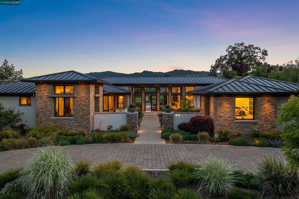 Meticulously designed contemporary estate located in the esteemed gated community of Alamo Springs. This magnificent home offers a south/west view of the Las Trampas Hills. Enter the grand foyer as you’re captivated by stunning floor-to-ceiling windows & soaring luxury light fixtures. Chef’s kitchen w/ high end appliances opens conveniently to the oversized family room & backyard through bronze clad pocket doors immersing you in indoor/outdoor living. Primary suite features a beautiful fireplace, spa inspired bathroom w/ multiple European shower heads, & spacious walk-in closet. Enjoy 3 additional bedrooms, 2 full & 2 half baths, as well as an office, bonus room & oversized laundry. Fabulous 750 bottle, climate controlled wine room with designer lighting. Serene backyard has a BBQ pavilion w/ Lynx appliances & granite countertops perfect for gatherings & ample space for a pool addition. Fire pits in both front & backyard offer tranquil places to enjoy company as well as lovely water features. 1 car garage & separate 3 car garage, both with electric chargers for any car enthusiast, & at least 6 more parking spaces in the driveways. Close to Iron Horse Trail, restaurants, shopping & all that Danville, Alamo & Walnut Creek have to offer. A 10+++.